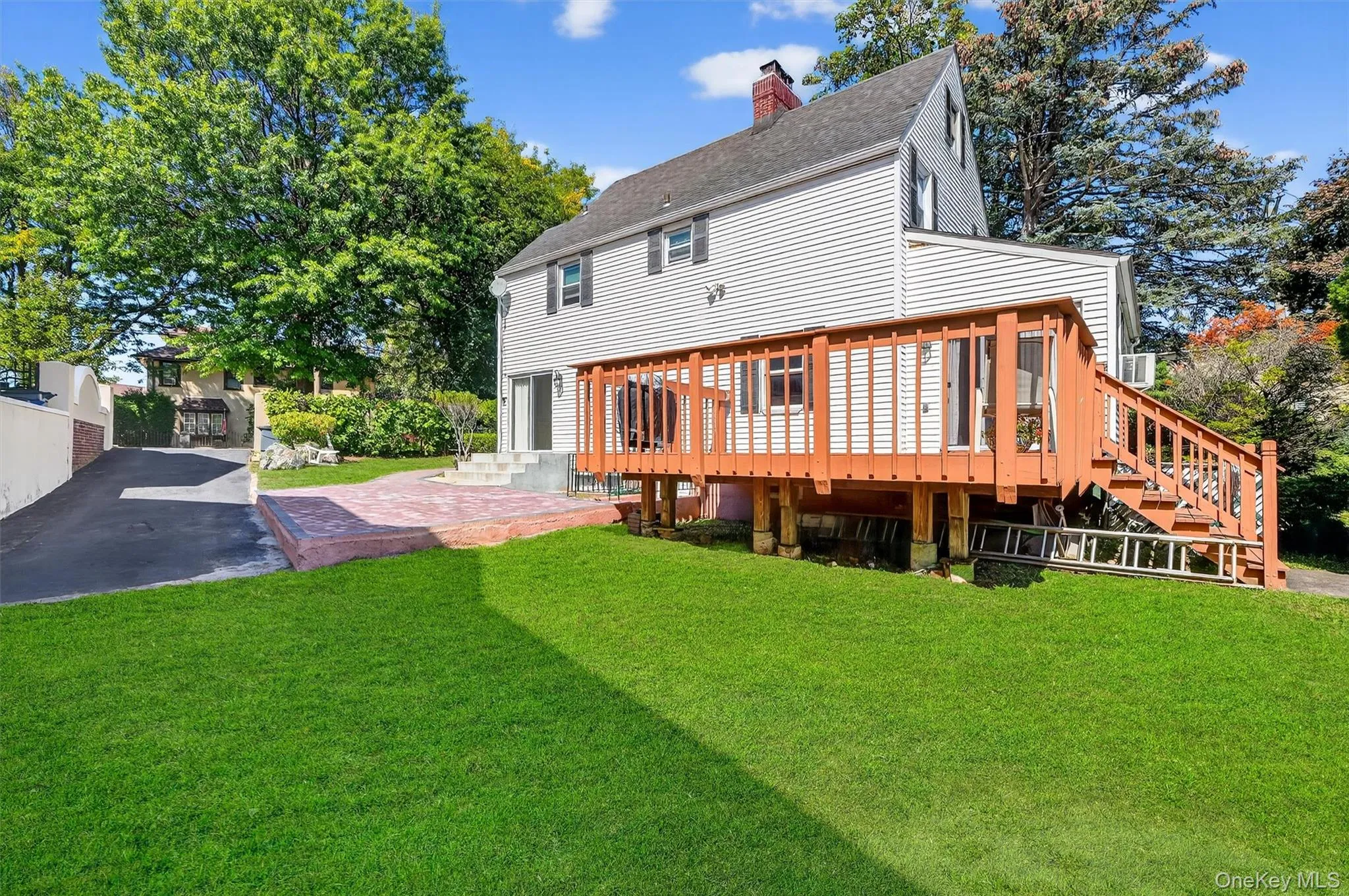 Back of house with a lawn, a chimney, a shingled roof, and a wooden deck Back of house with a lawn, a chimney, a shingled roof, and a wooden deck
