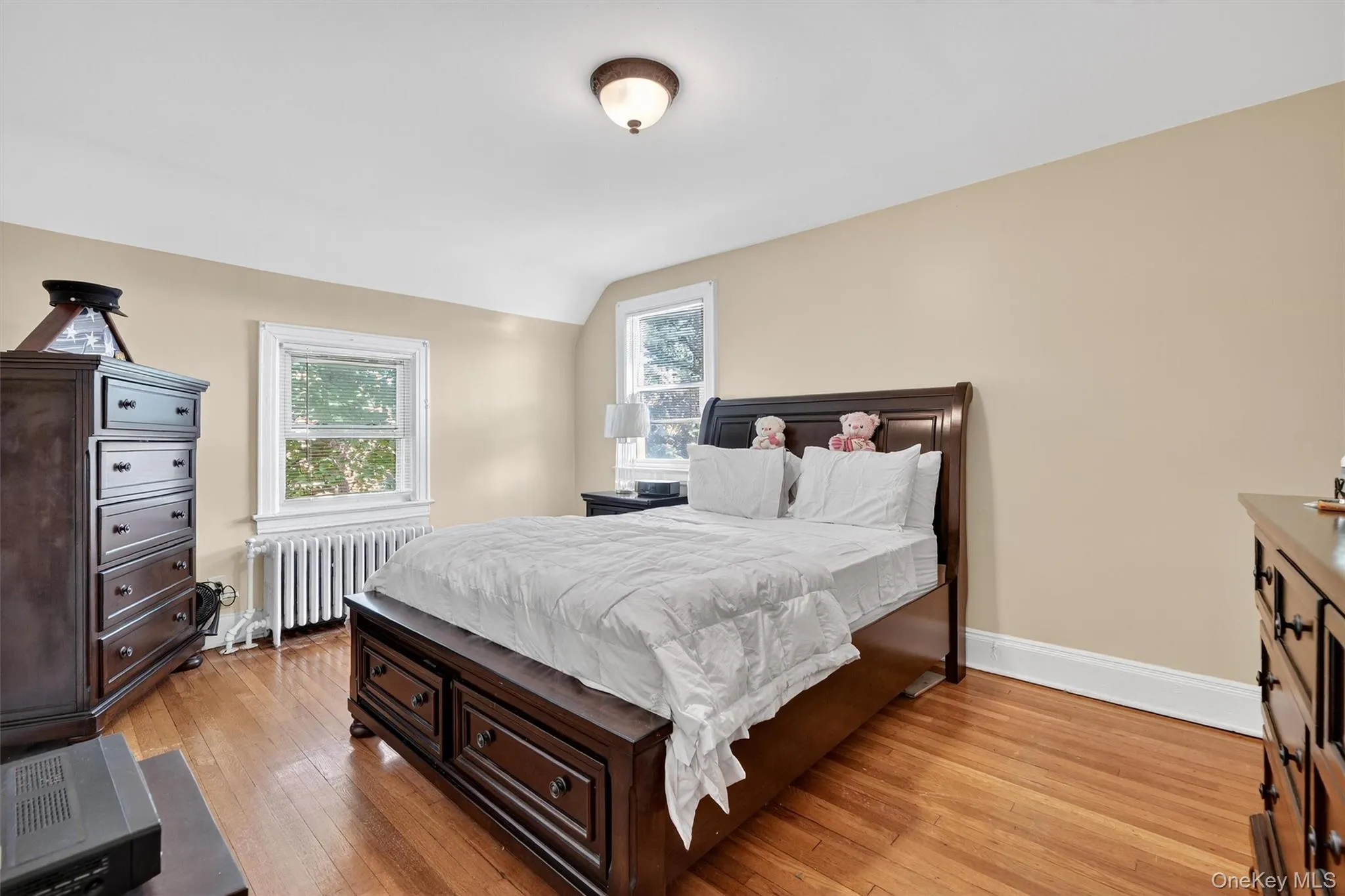 Bedroom with light wood finished floors, radiator heating unit, and lofted ceiling Bedroom with light wood finished floors, radiator heating unit, and lofted ceiling