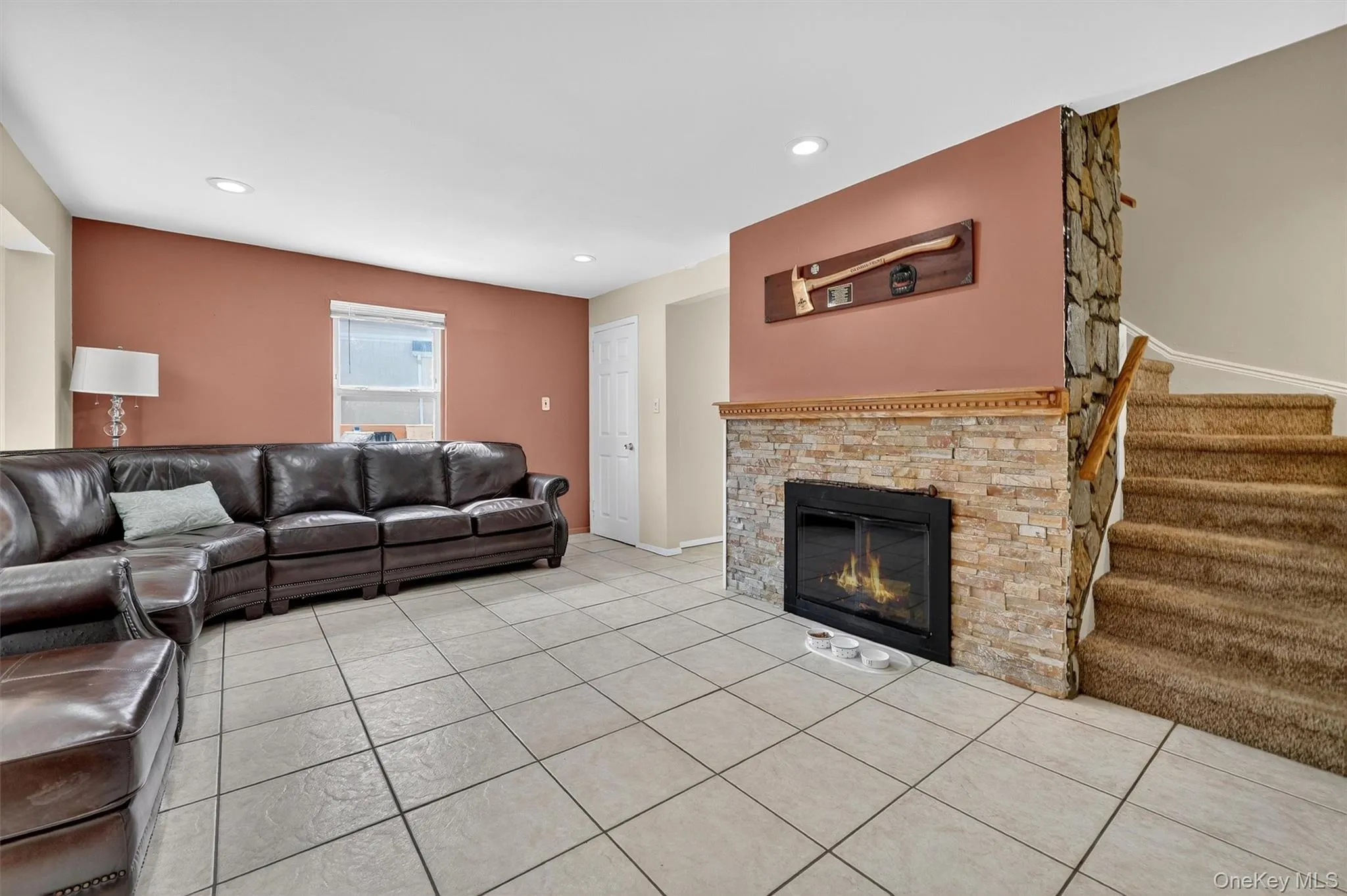 Living room with light tile patterned floors, a glass covered fireplace, recessed lighting, and stairs Living room with light tile patterned floors, a glass covered fireplace, recessed lighting, and stairs
