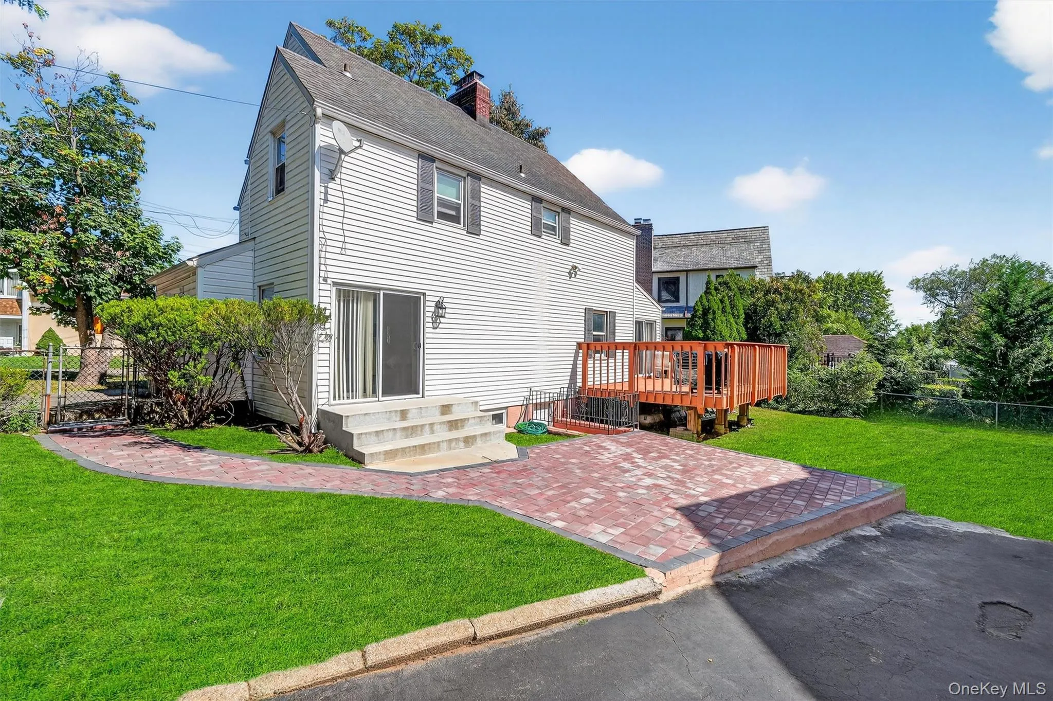 Back of property with a patio, a wooden deck, and a chimney Back of property with a patio, a wooden deck, and a chimney