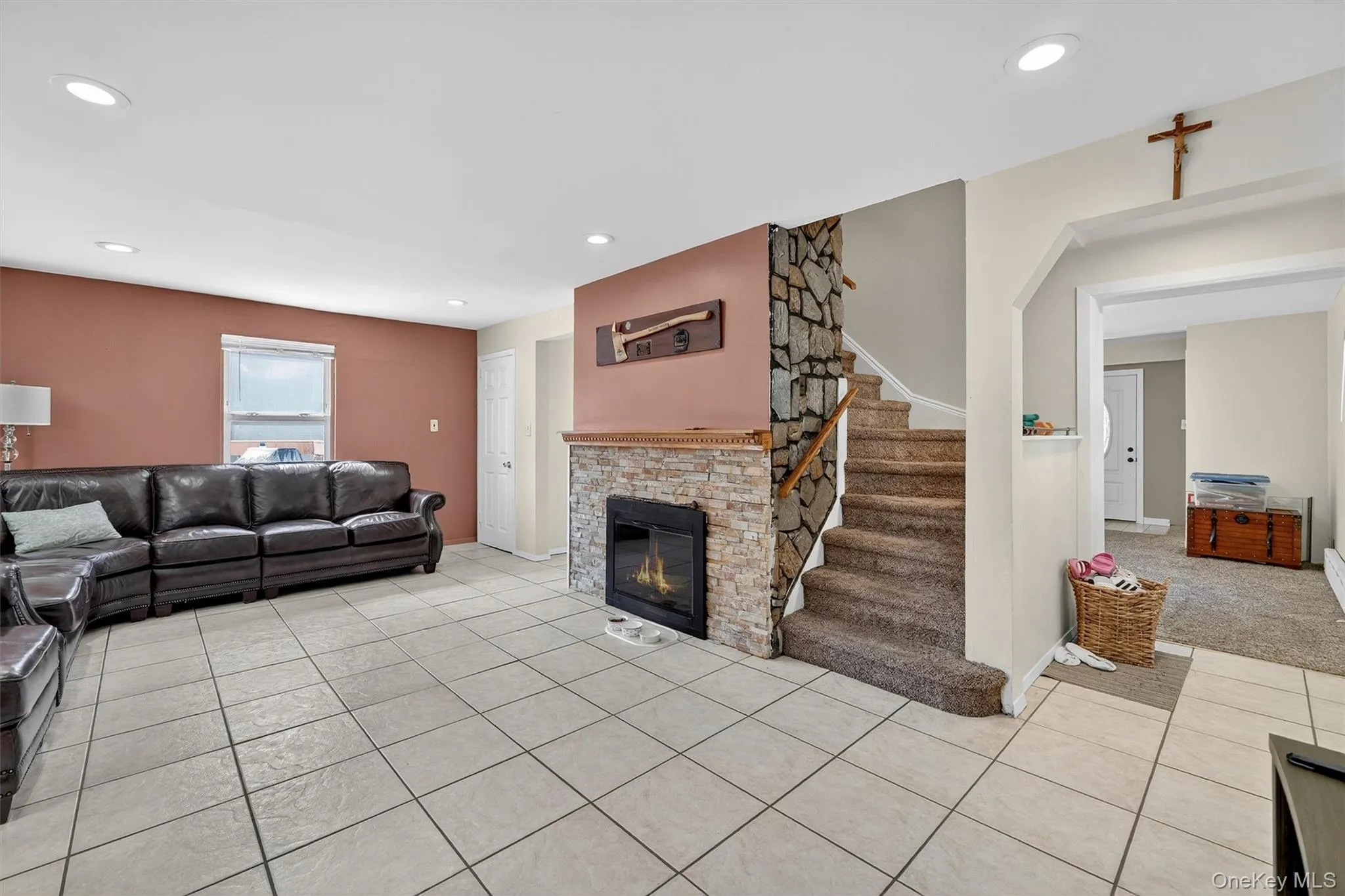 Living room featuring light tile patterned floors, a stone fireplace, recessed lighting, and stairway Living room featuring light tile patterned floors, a stone fireplace, recessed lighting, and stairway