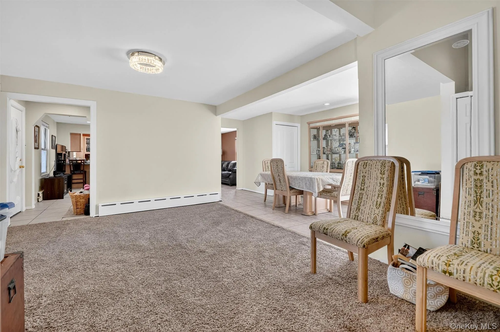 Living area featuring light tile patterned floors, light carpet, and a baseboard heating unit Living area featuring light tile patterned floors, light carpet, and a baseboard heating unit