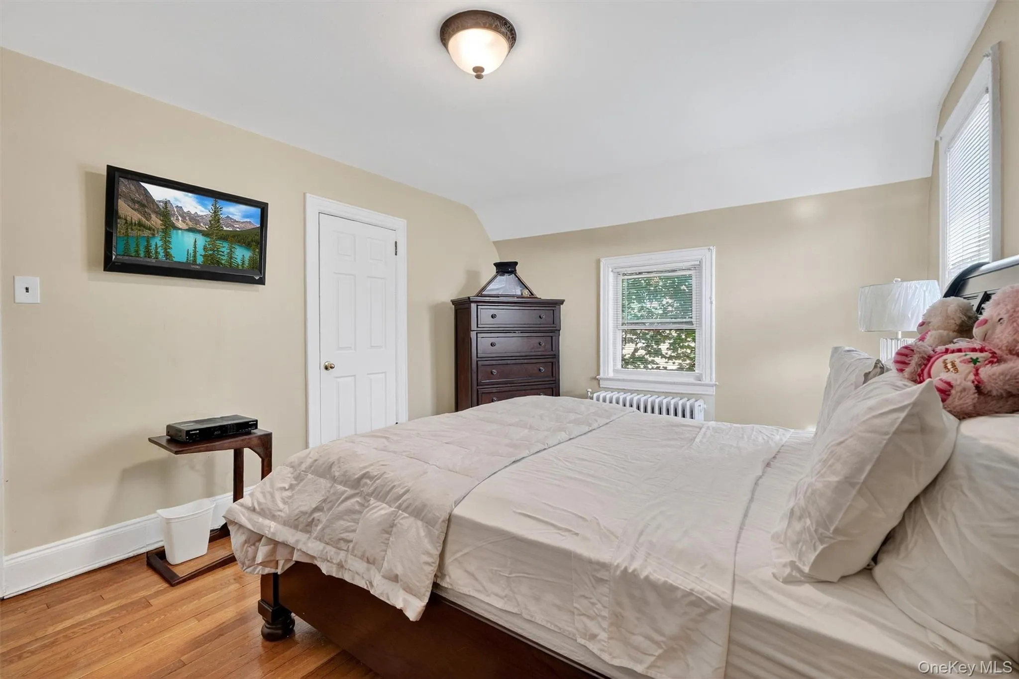Bedroom featuring light wood finished floors, radiator heating unit, and vaulted ceiling Bedroom featuring light wood finished floors, radiator heating unit, and vaulted ceiling
