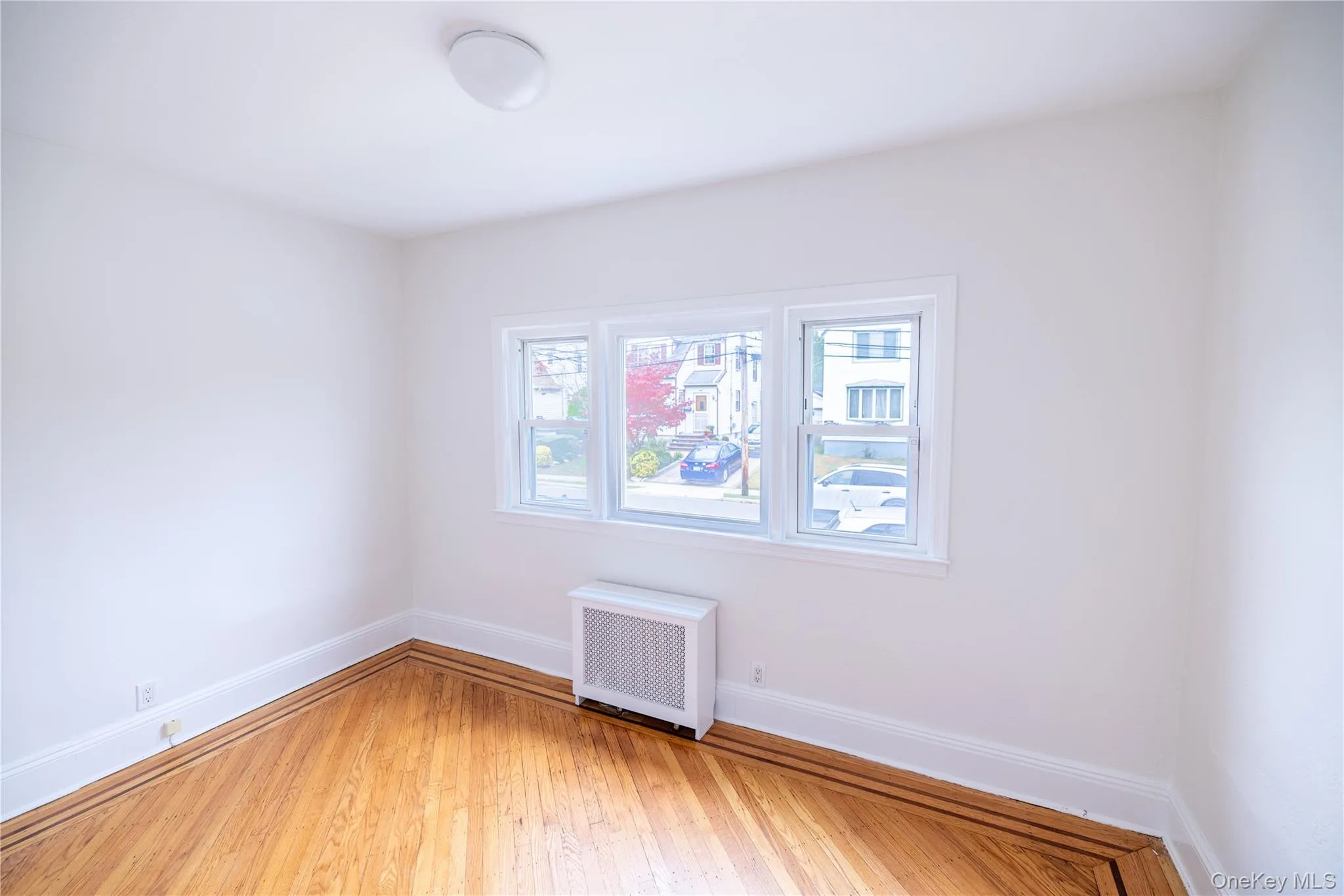 Empty room with radiator and hardwood / wood-style floors Empty room with radiator and hardwood / wood-style floors