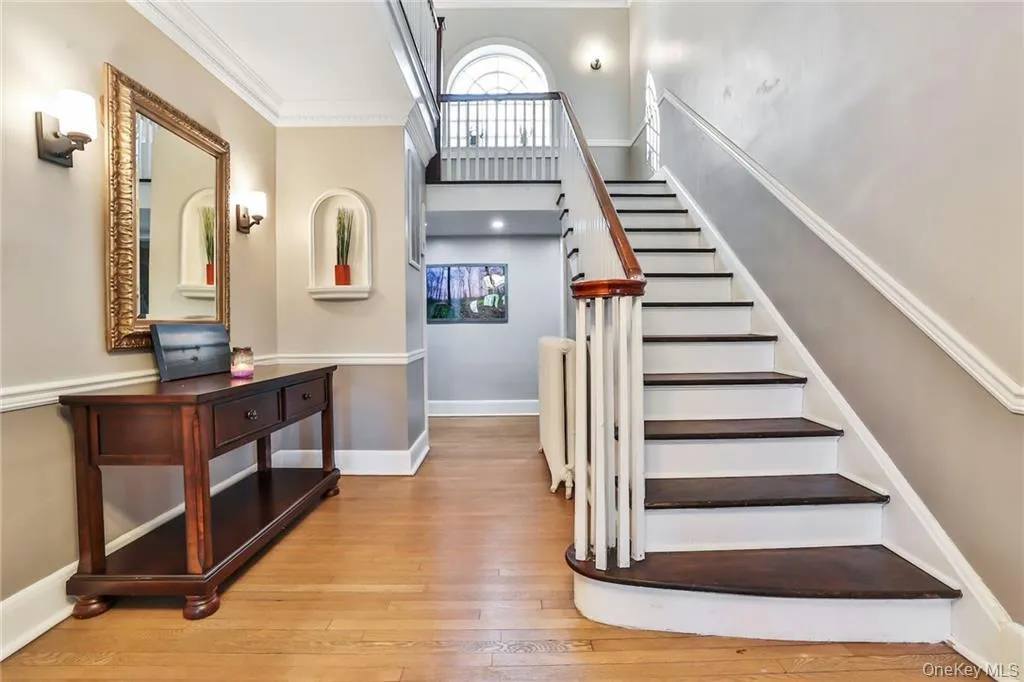 Stairs with wood-type flooring, ornamental molding, radiator heating unit, and a high ceiling Stairs with wood-type flooring, ornamental molding, radiator heating unit, and a high ceiling