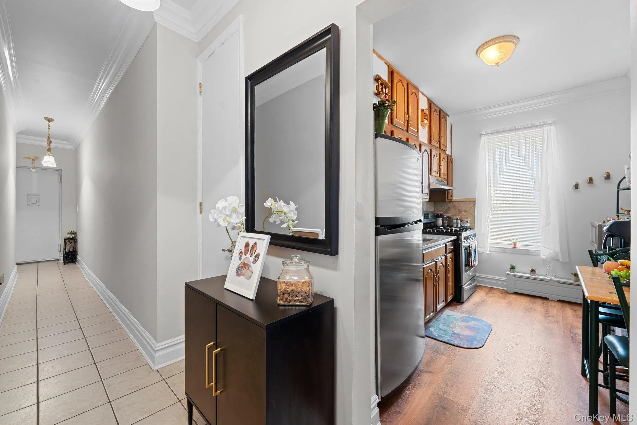Kitchen with crown molding, stainless steel appliances, brown cabinets, a baseboard heating unit, and pendant lighting Kitchen with crown molding, stainless steel appliances, brown cabinets, a baseboard heating unit, and pendant lighting