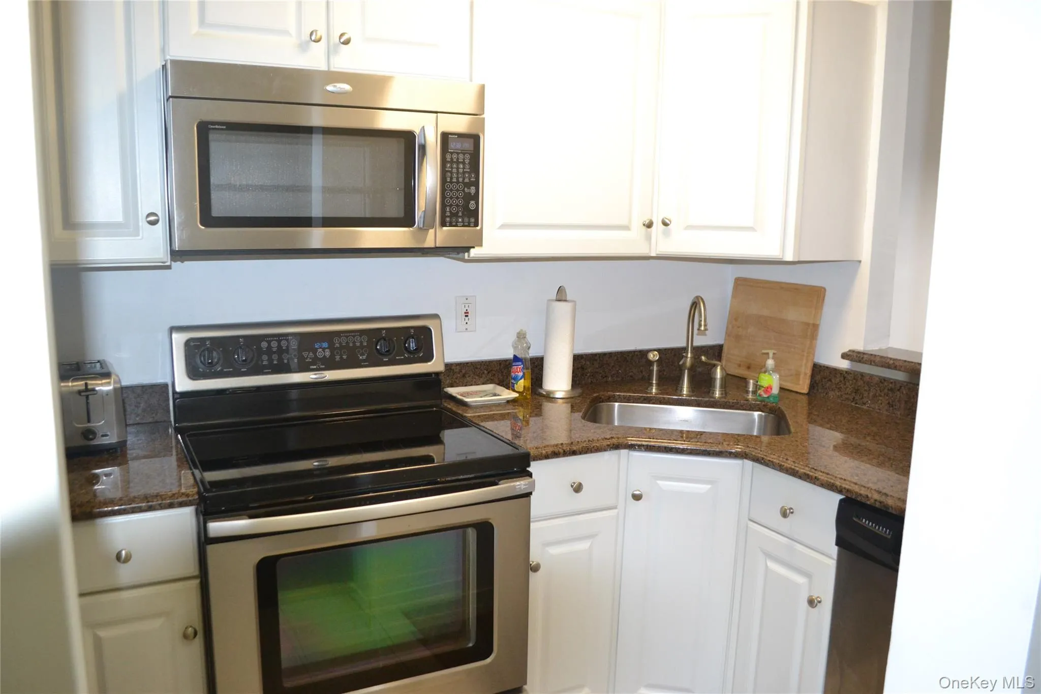 Kitchen with appliances with stainless steel finishes, white cabinets, and dark stone countertops Kitchen with appliances with stainless steel finishes, white cabinets, and dark stone countertops