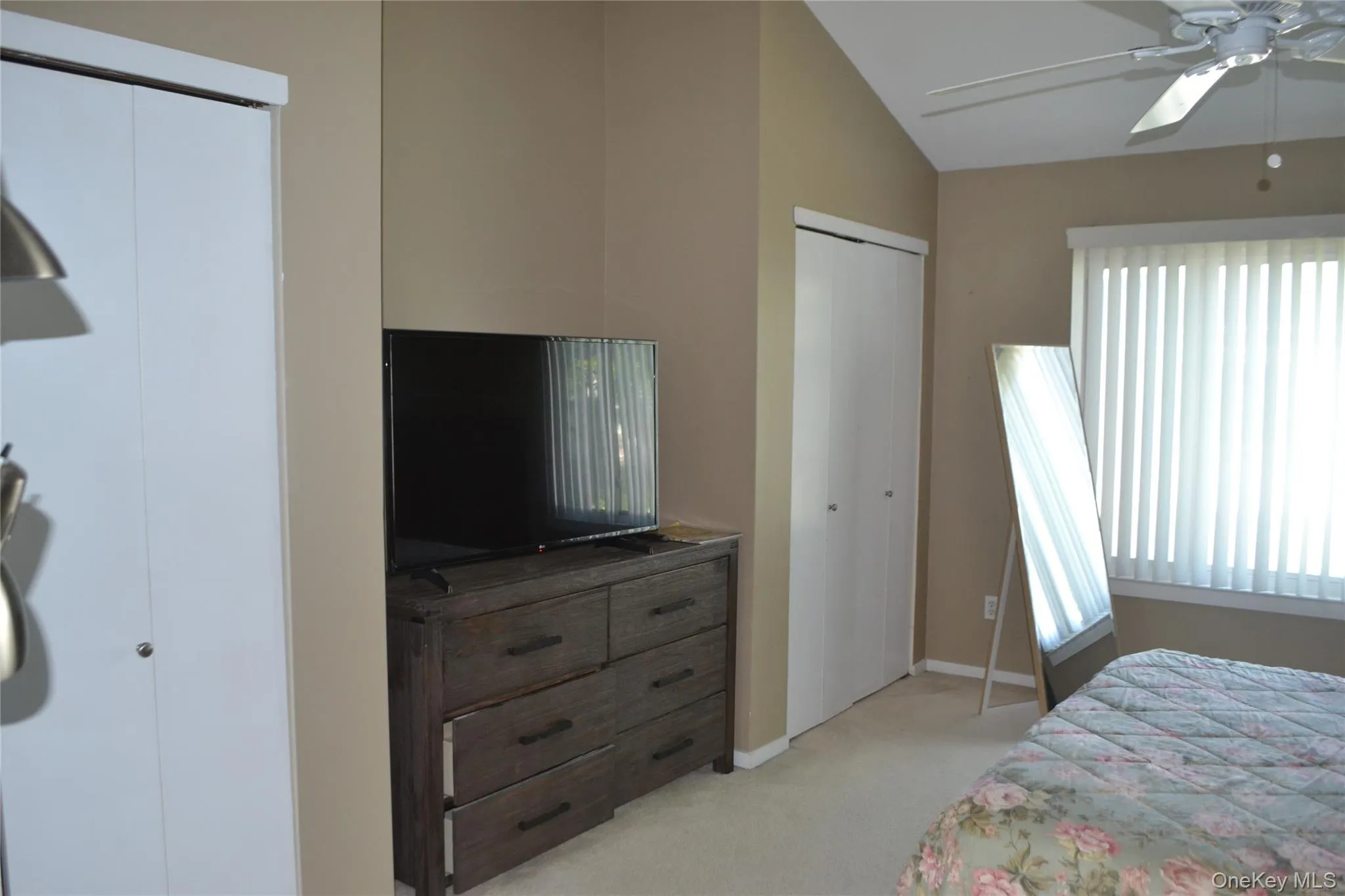 Bedroom featuring multiple closets, light carpet, ceiling fan, and lofted ceiling Bedroom featuring multiple closets, light carpet, ceiling fan, and lofted ceiling