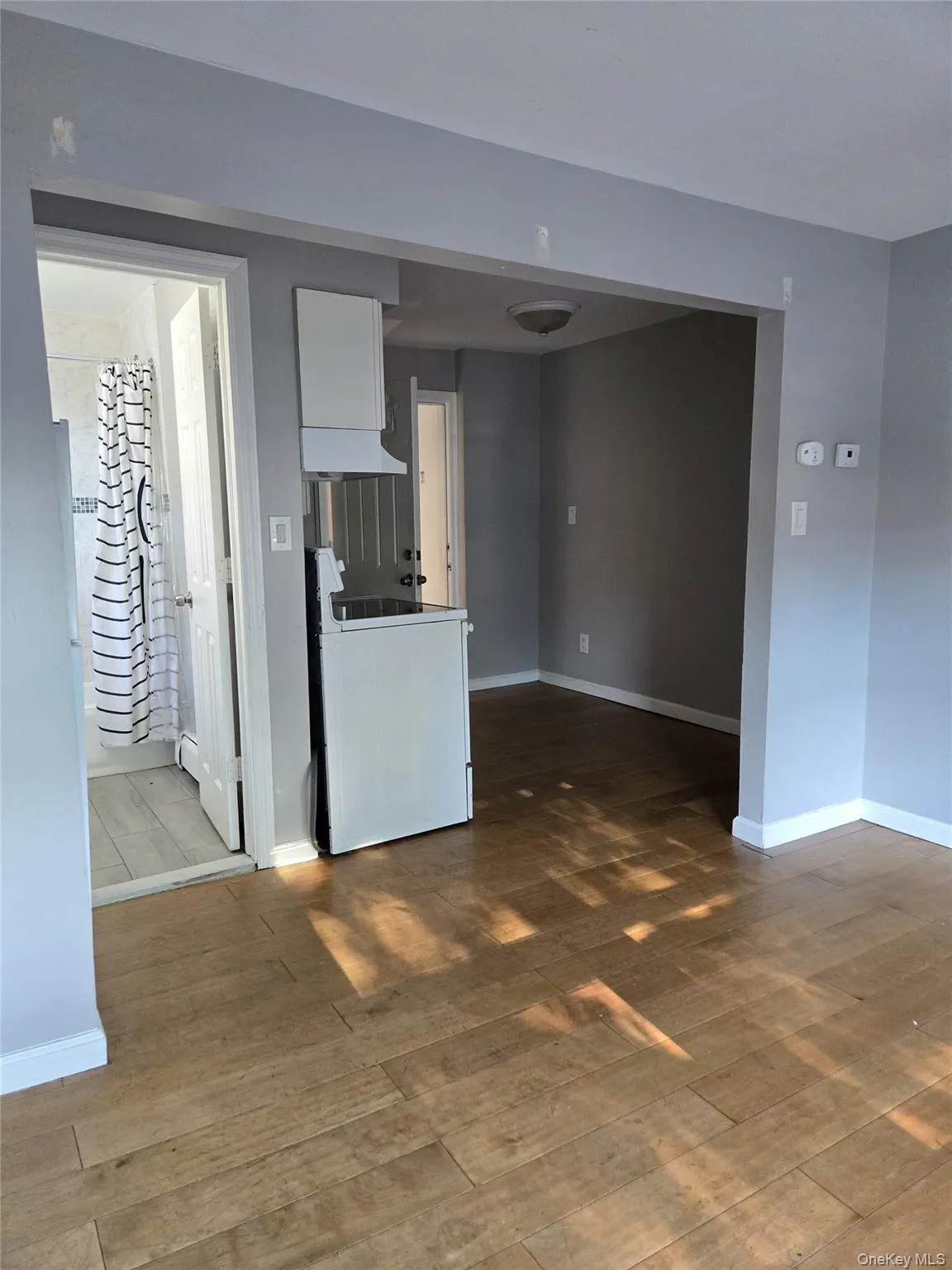 Unfurnished living room featuring dark wood-type flooring and baseboards Unfurnished living room featuring dark wood-type flooring and baseboards