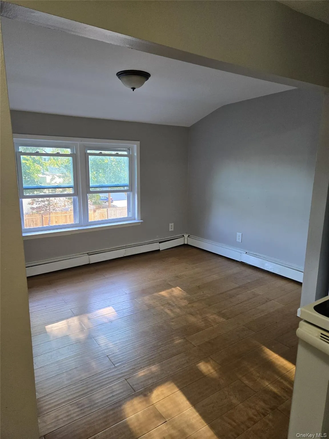Empty room with baseboard heating and dark wood-style flooring Empty room with baseboard heating and dark wood-style flooring