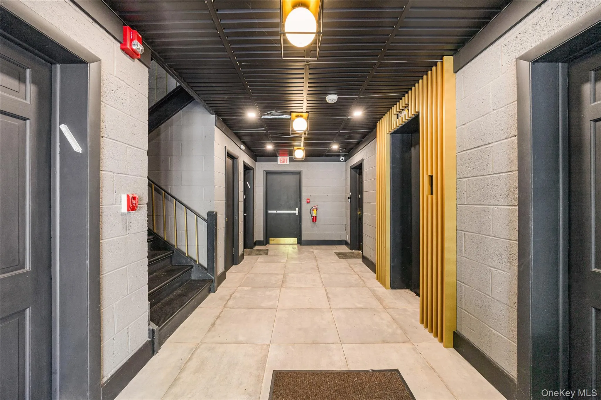 Hallway with concrete block wall, elevator, light tile patterned floors, and stairway Hallway with concrete block wall, elevator, light tile patterned floors, and stairway
