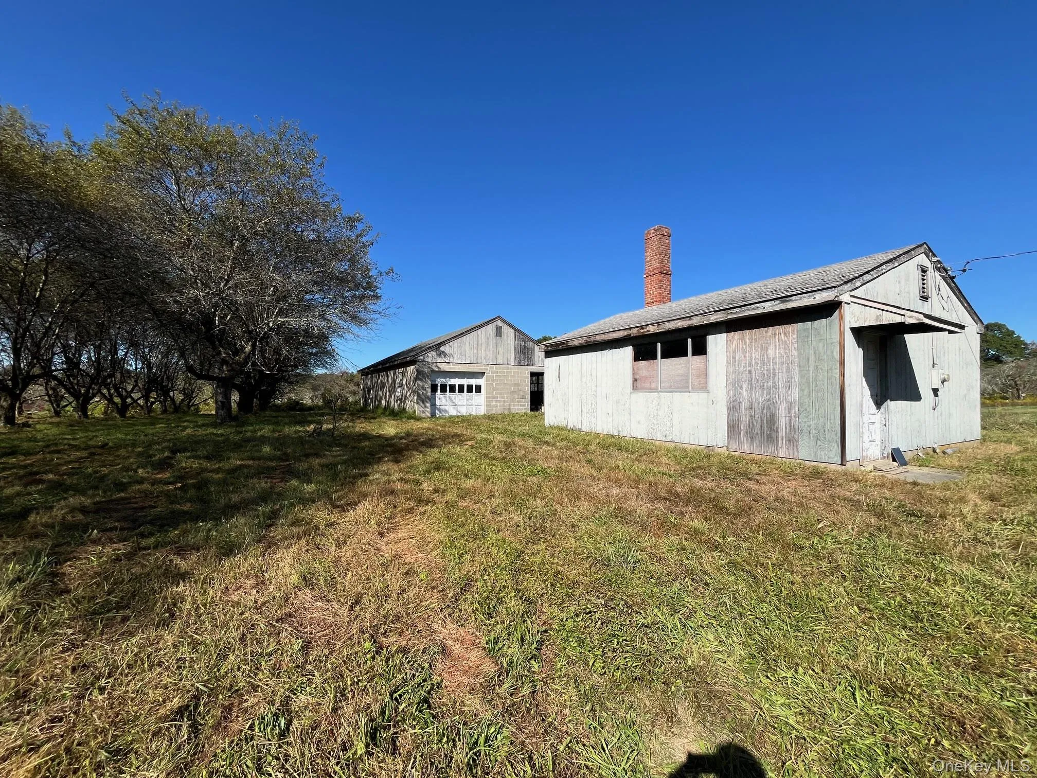 Back of property featuring an outbuilding, a chimney, and a lawn Back of property featuring an outbuilding, a chimney, and a lawn