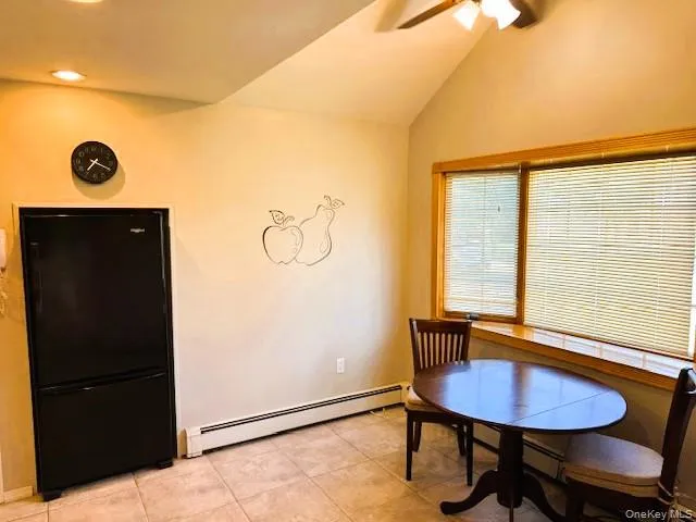 Dining space with a baseboard heating unit, light tile patterned flooring, lofted ceiling, and a ceiling fan Dining space with a baseboard heating unit, light tile patterned flooring, lofted ceiling, and a ceiling fan