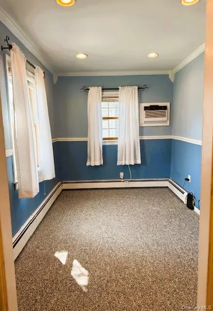 Carpeted spare room featuring crown molding, baseboard heating, recessed lighting, and a wall mounted AC Carpeted spare room featuring crown molding, baseboard heating, recessed lighting, and a wall mounted AC