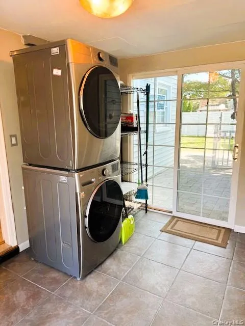 Washroom featuring tile patterned floors and stacked washing machine and dryer Washroom featuring tile patterned floors and stacked washing machine and dryer