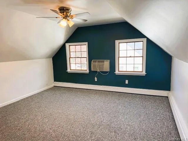 Additional living space with carpet floors, a baseboard heating unit, vaulted ceiling, a wall mounted AC, and a ceiling fan Additional living space with carpet floors, a baseboard heating unit, vaulted ceiling, a wall mounted AC, and a ceiling fan