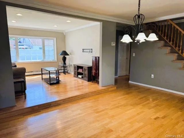 Dining space featuring wood finished floors, a chandelier, ornamental molding, stairs, and recessed lighting Dining space featuring wood finished floors, a chandelier, ornamental molding, stairs, and recessed lighting