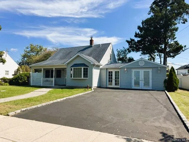 View of front of house with french doors, covered porch, a front lawn, asphalt driveway, and a shingled roof View of front of house with french doors, covered porch, a front lawn, asphalt driveway, and a shingled roof