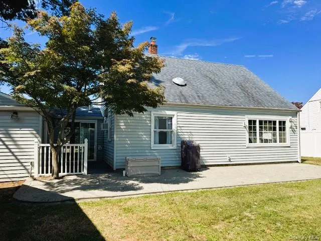 Back of property featuring a patio area, a lawn, roof with shingles, and a chimney Back of property featuring a patio area, a lawn, roof with shingles, and a chimney