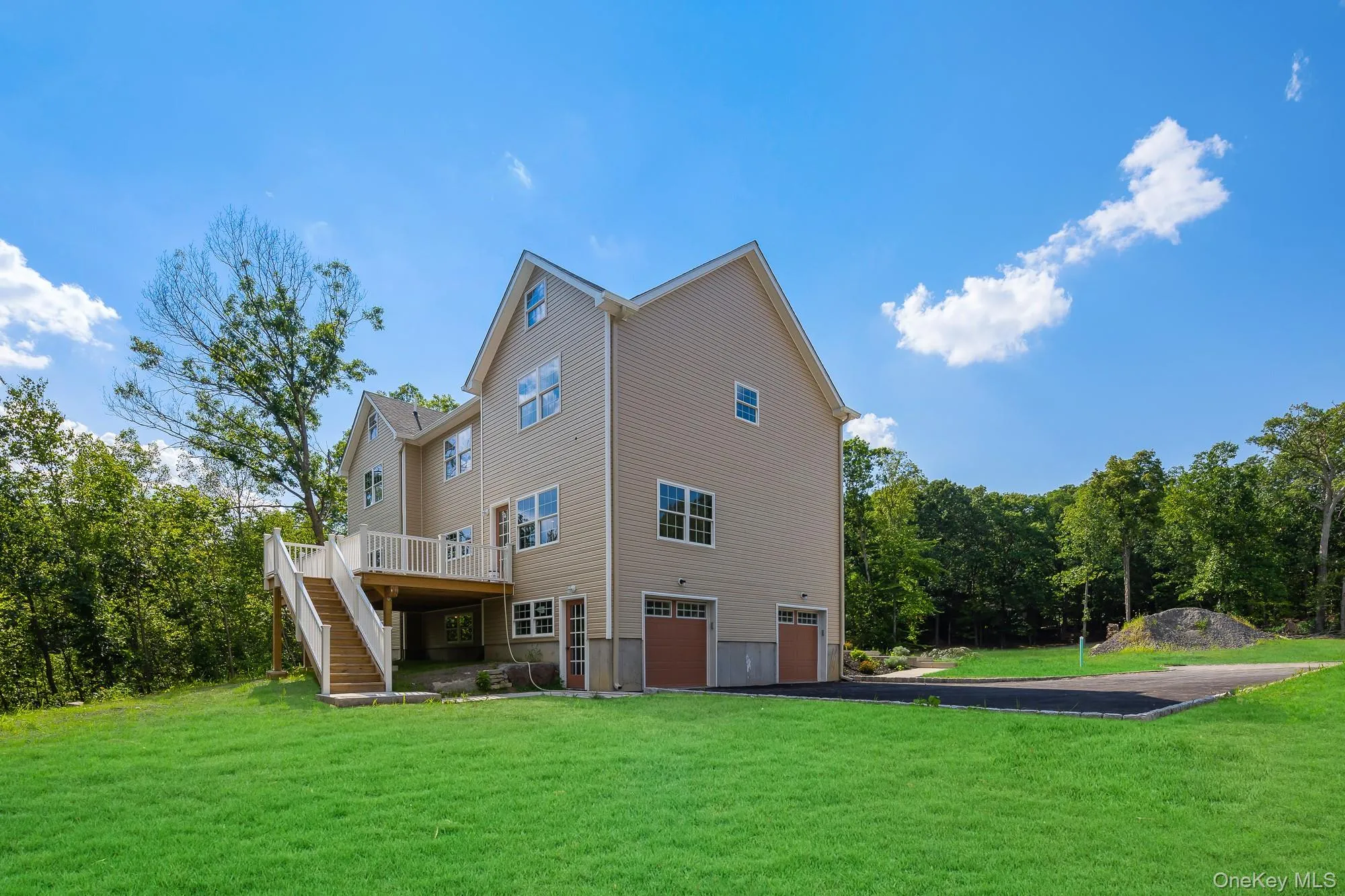 Back of house featuring an attached garage, aphalt driveway, stairs, a yard, and a deck Back of house featuring an attached garage, aphalt driveway, stairs, a yard, and a deck