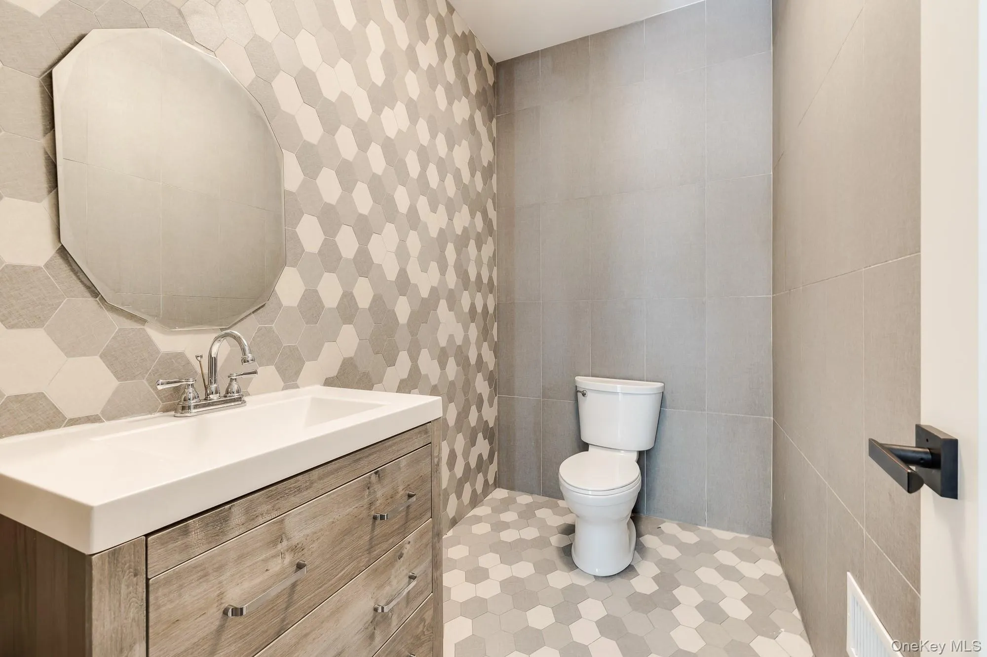 Half bathroom with toilet, tile patterned flooring, tile walls, and vanity Half bathroom with toilet, tile patterned flooring, tile walls, and vanity
