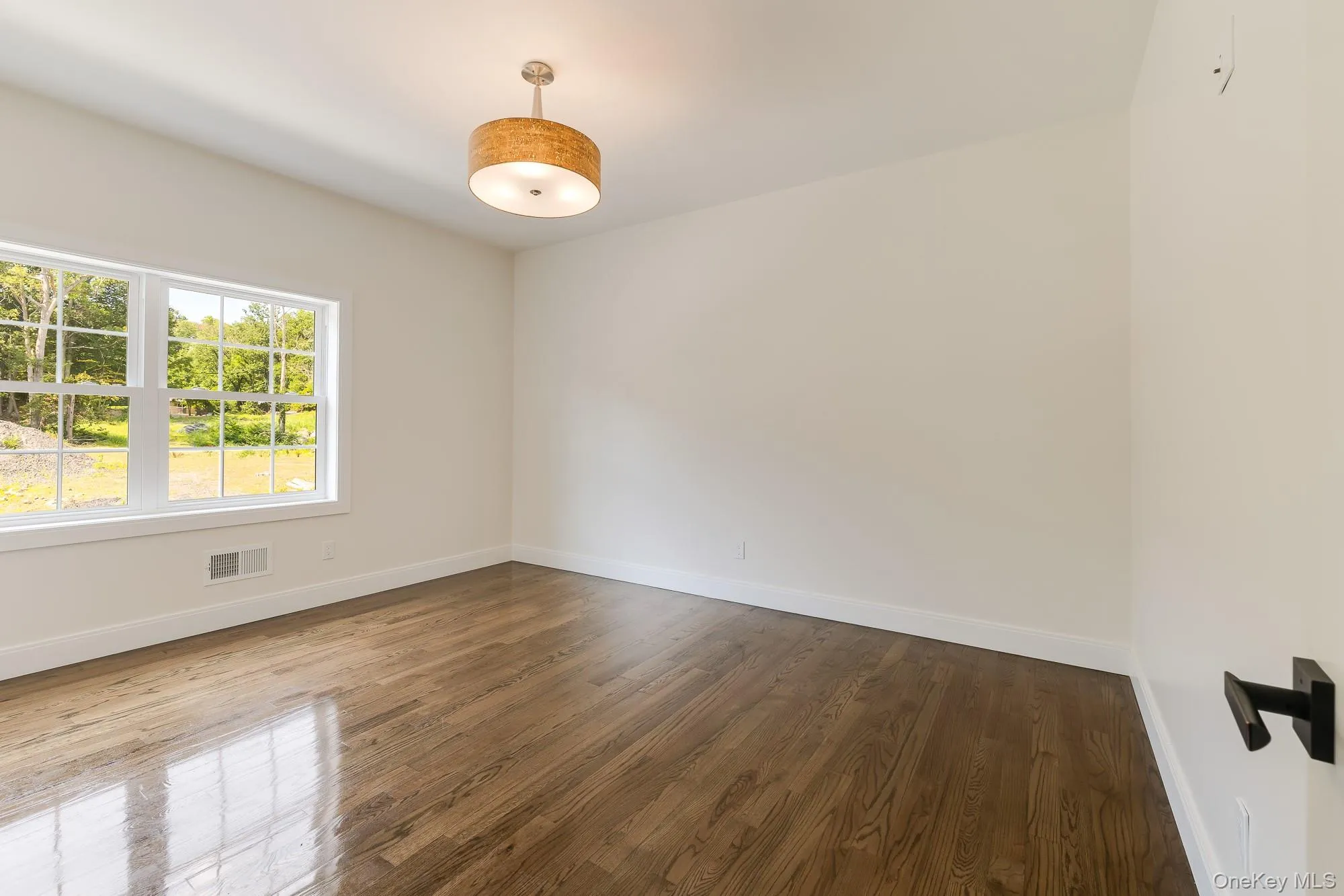 Empty room with visible vents, baseboards, and dark wood-style floors Empty room with visible vents, baseboards, and dark wood-style floors