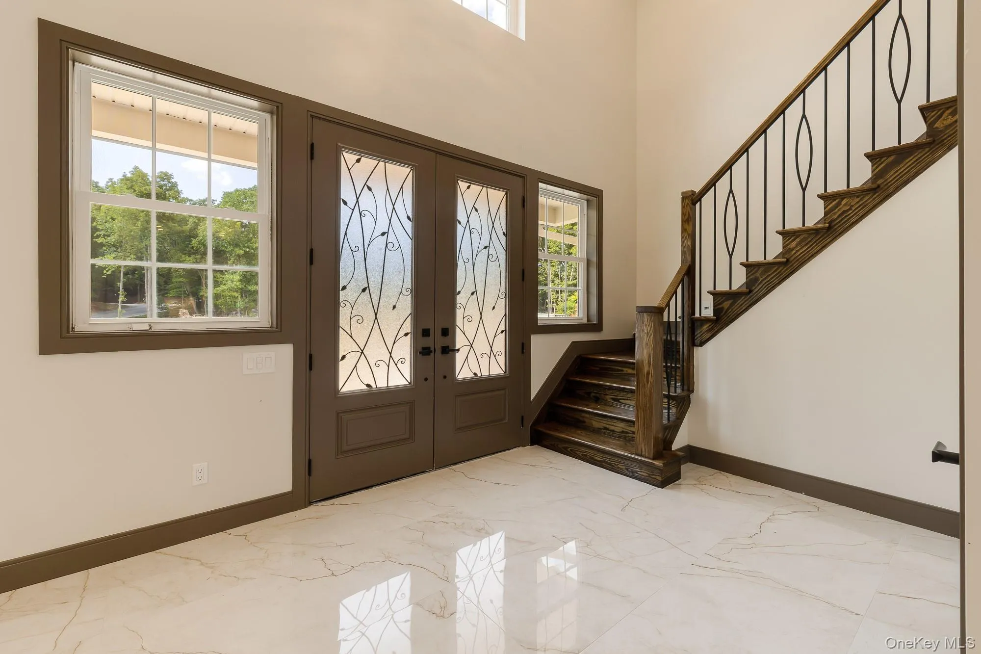 Entrance foyer featuring french doors, a wealth of natural light, and marble finish floor Entrance foyer featuring french doors, a wealth of natural light, and marble finish floor