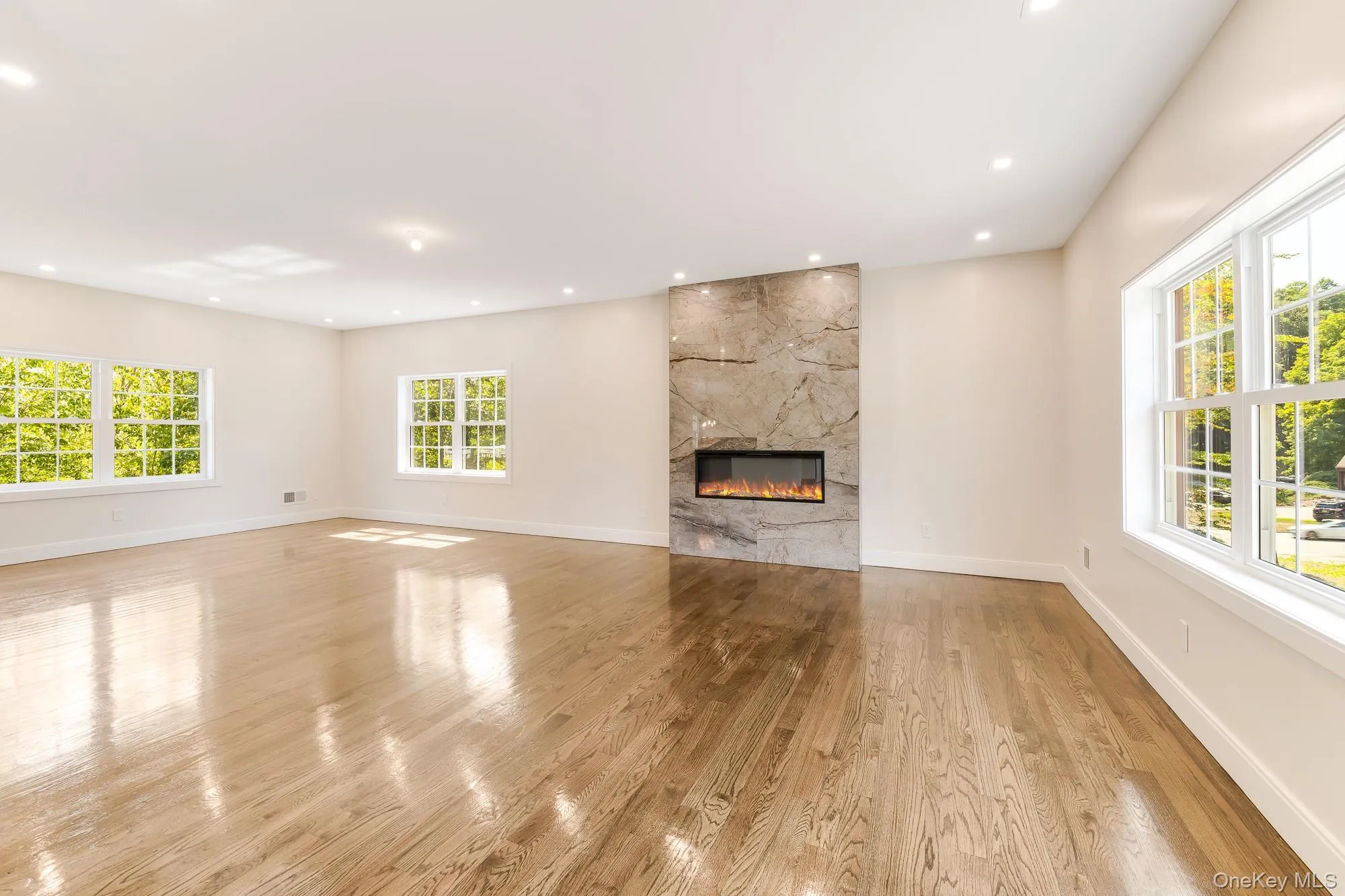 Unfurnished living room featuring light wood-type flooring, and a premium fireplace Unfurnished living room featuring light wood-type flooring, and a premium fireplace