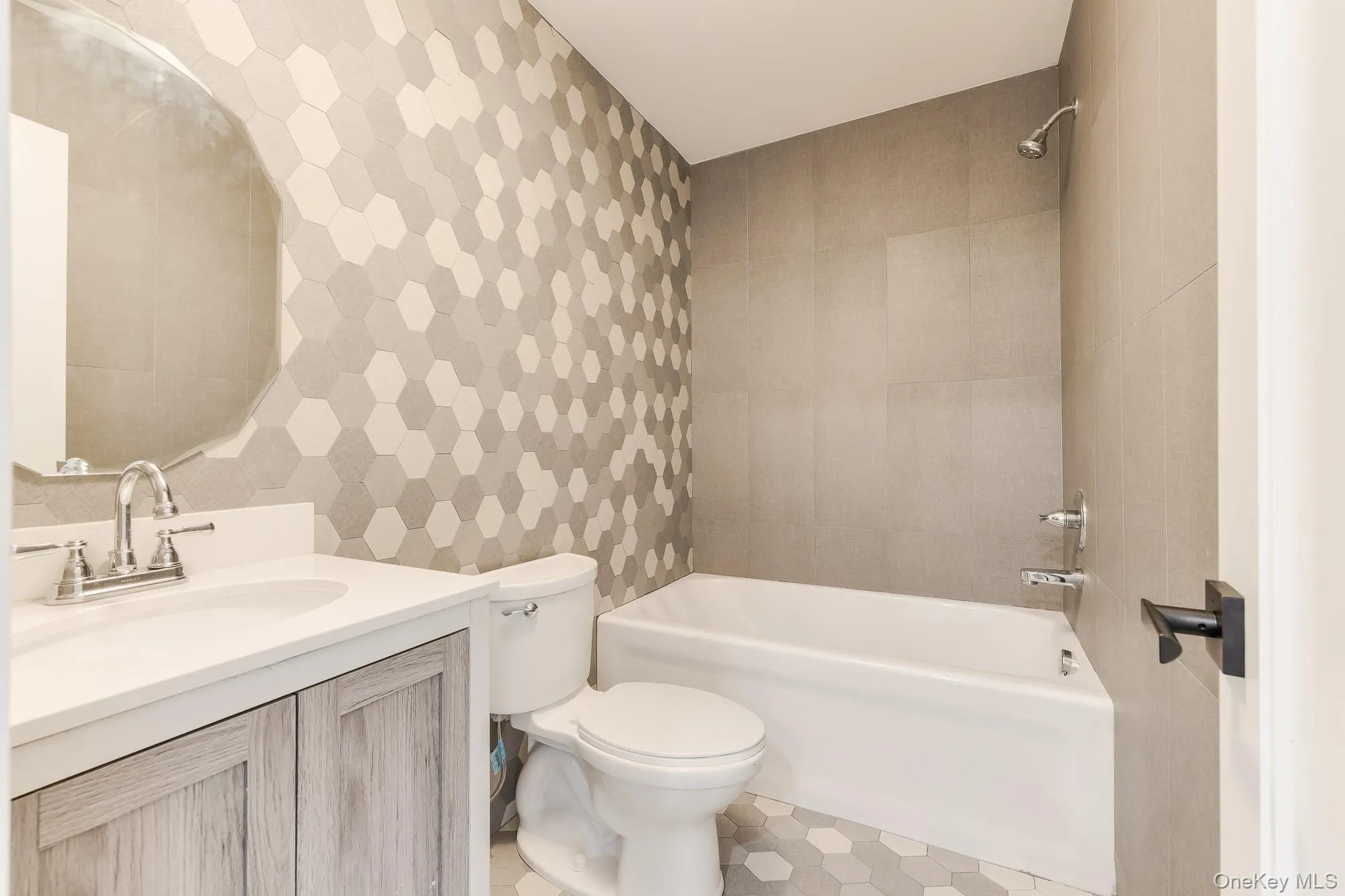 Bathroom featuring vanity, tile patterned floors, bathing tub / shower combination, toilet, and tile walls Bathroom featuring vanity, tile patterned floors, bathing tub / shower combination, toilet, and tile walls