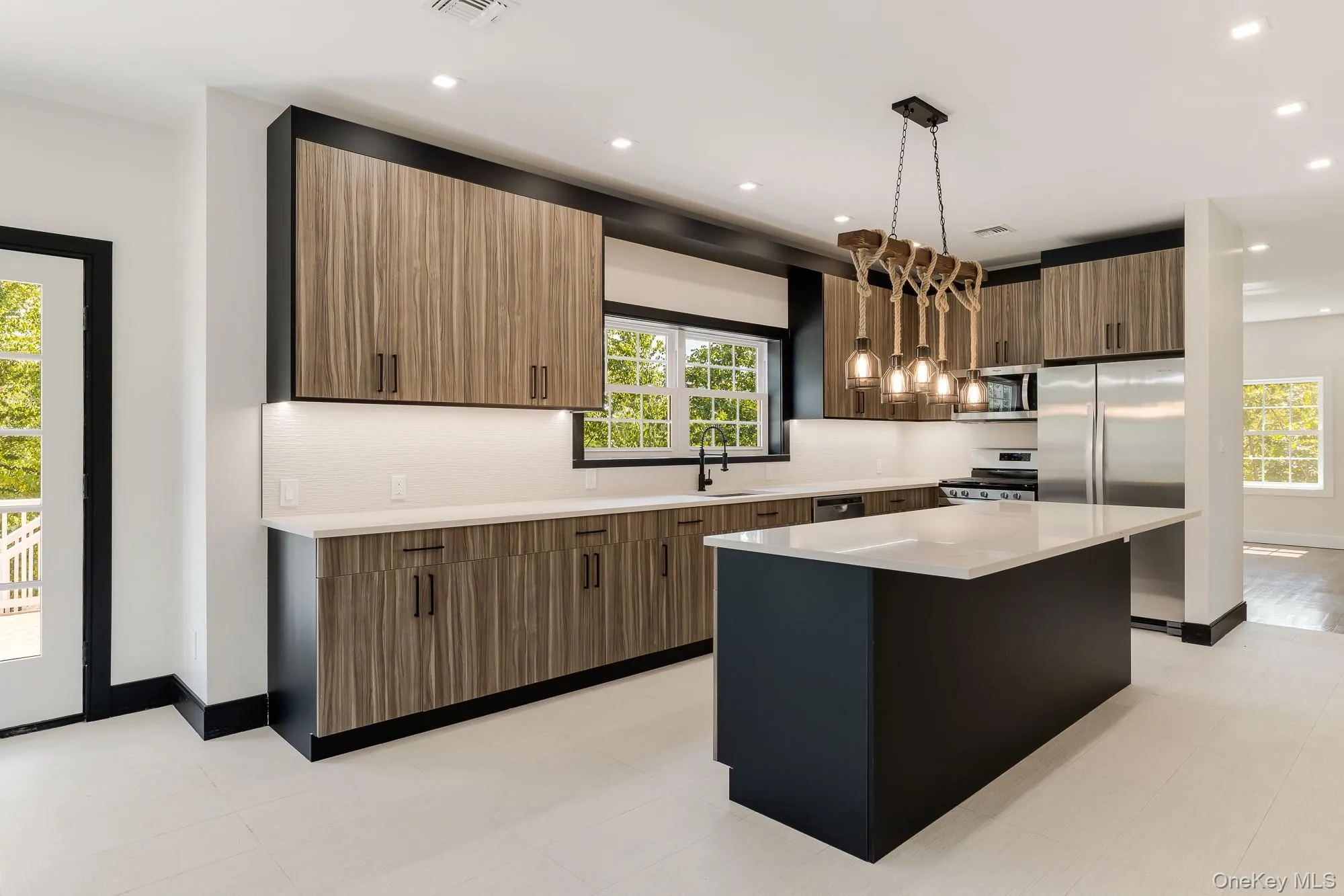 Kitchen featuring a center island, light countertops, modern cabinets, appliances with stainless steel finishes, and a sink Kitchen featuring a center island, light countertops, modern cabinets, appliances with stainless steel finishes, and a sink