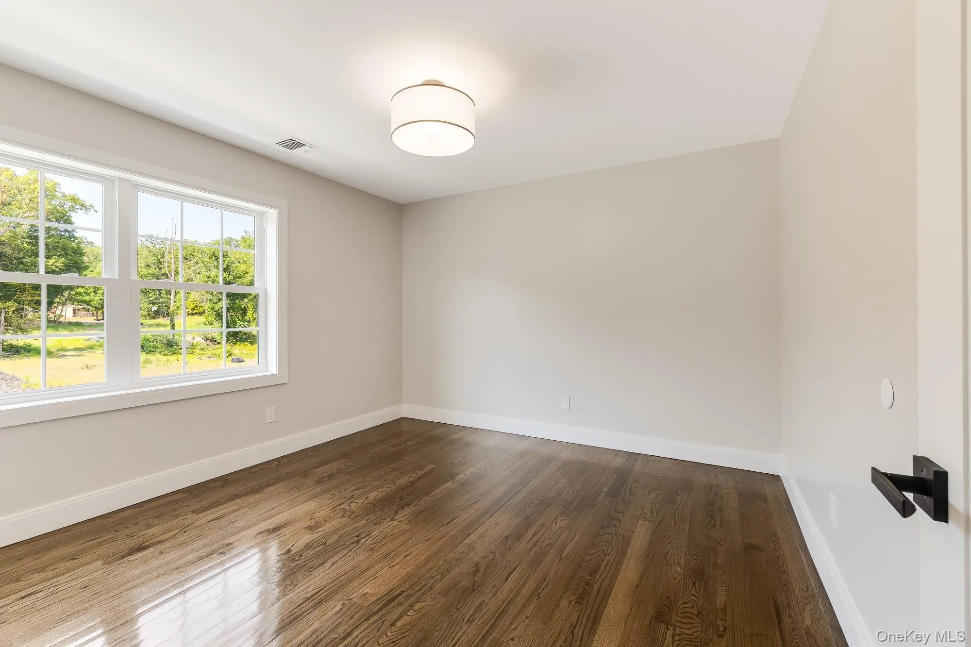 Spare room featuring dark wood-type flooring, and visible vents Spare room featuring dark wood-type flooring, and visible vents