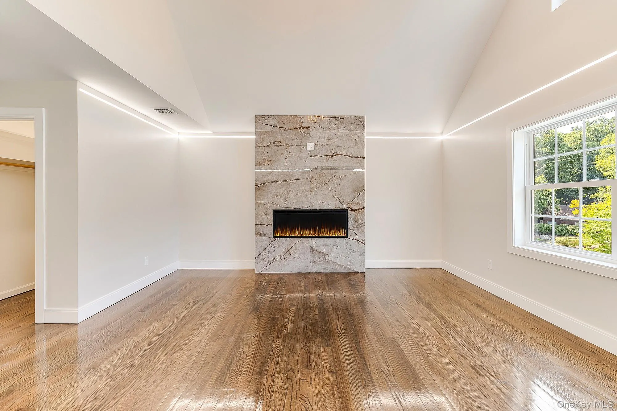 Unfurnished living room featuring plenty of natural light, wood finished floors, and lofted ceiling Unfurnished living room featuring plenty of natural light, wood finished floors, and lofted ceiling
