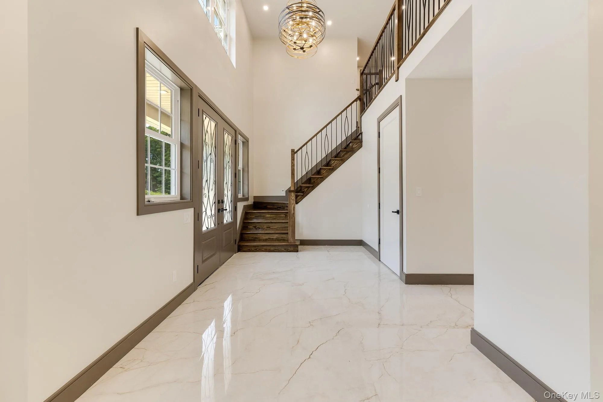 Foyer featuring a chandelier, marble finish floor, and stairs Foyer featuring a chandelier, marble finish floor, and stairs