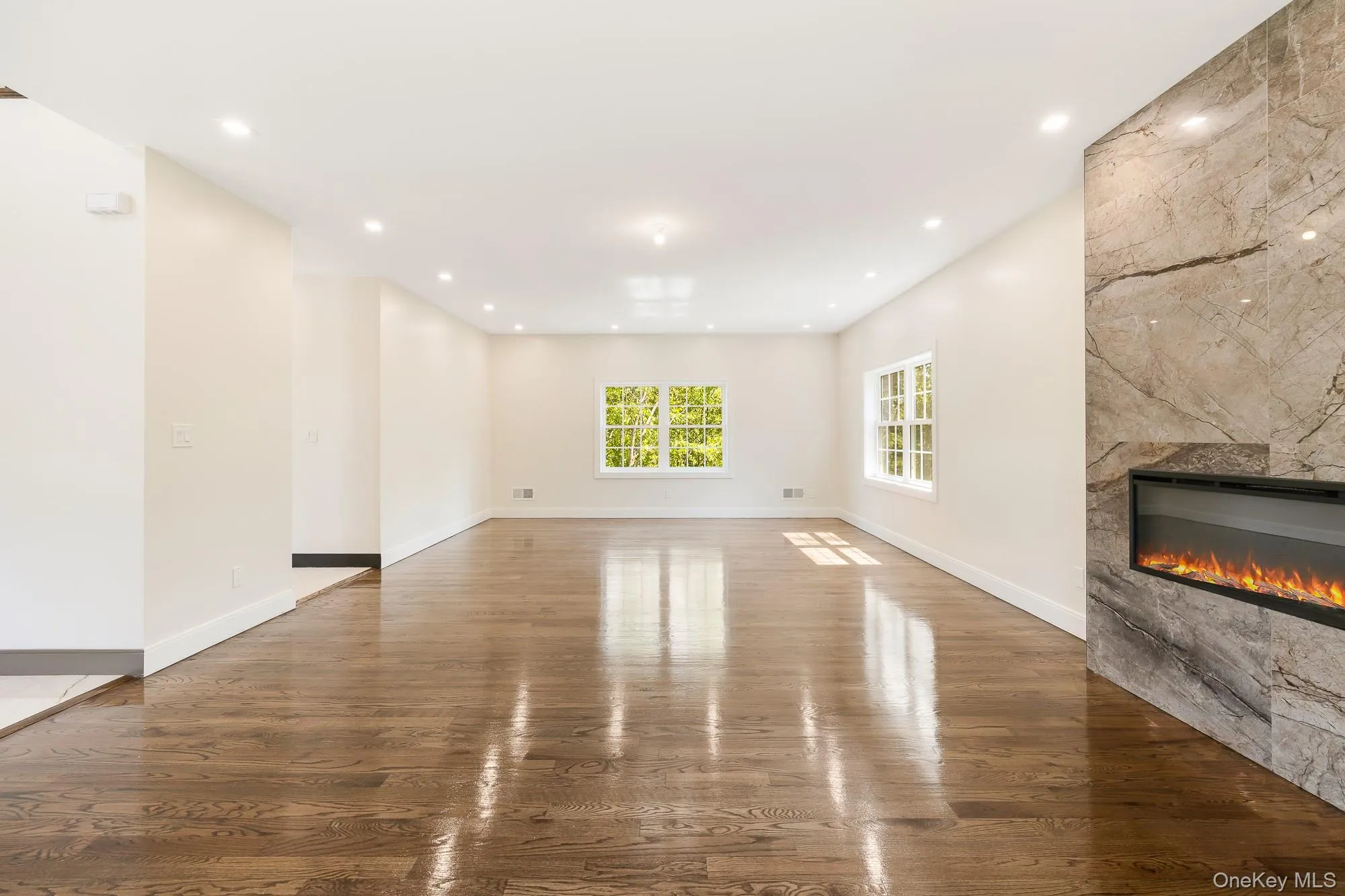 Unfurnished living room with wood finished floors, a tiled fireplace, and recessed lighting Unfurnished living room with wood finished floors, a tiled fireplace, and recessed lighting