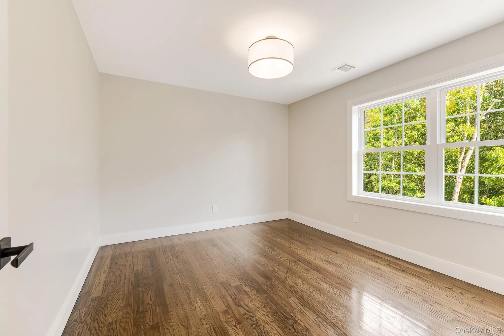 Empty room with wood finished floors, and visible vents Empty room with wood finished floors, and visible vents