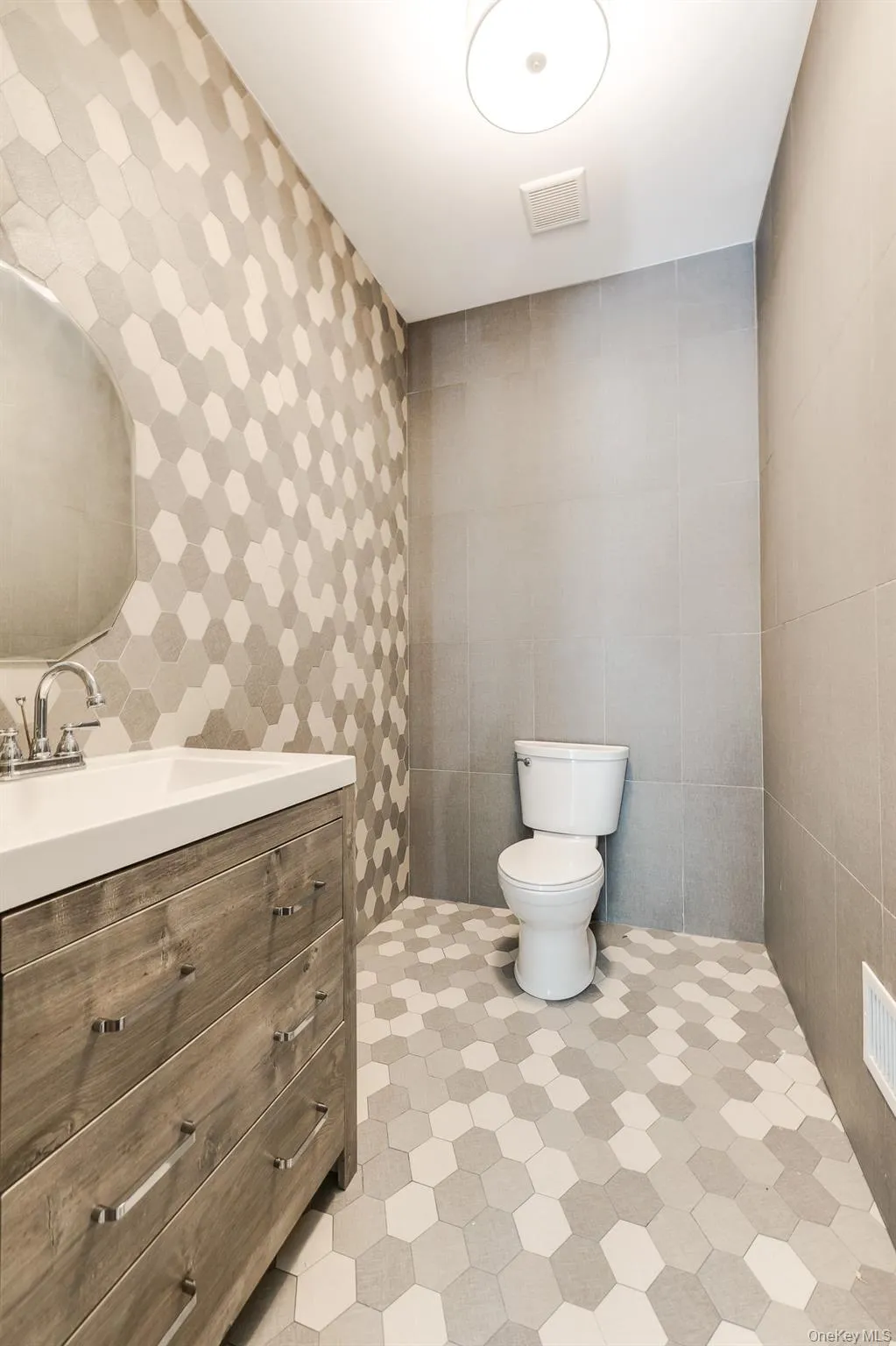 Bathroom featuring toilet, visible vents, tile walls, and vanity Bathroom featuring toilet, visible vents, tile walls, and vanity