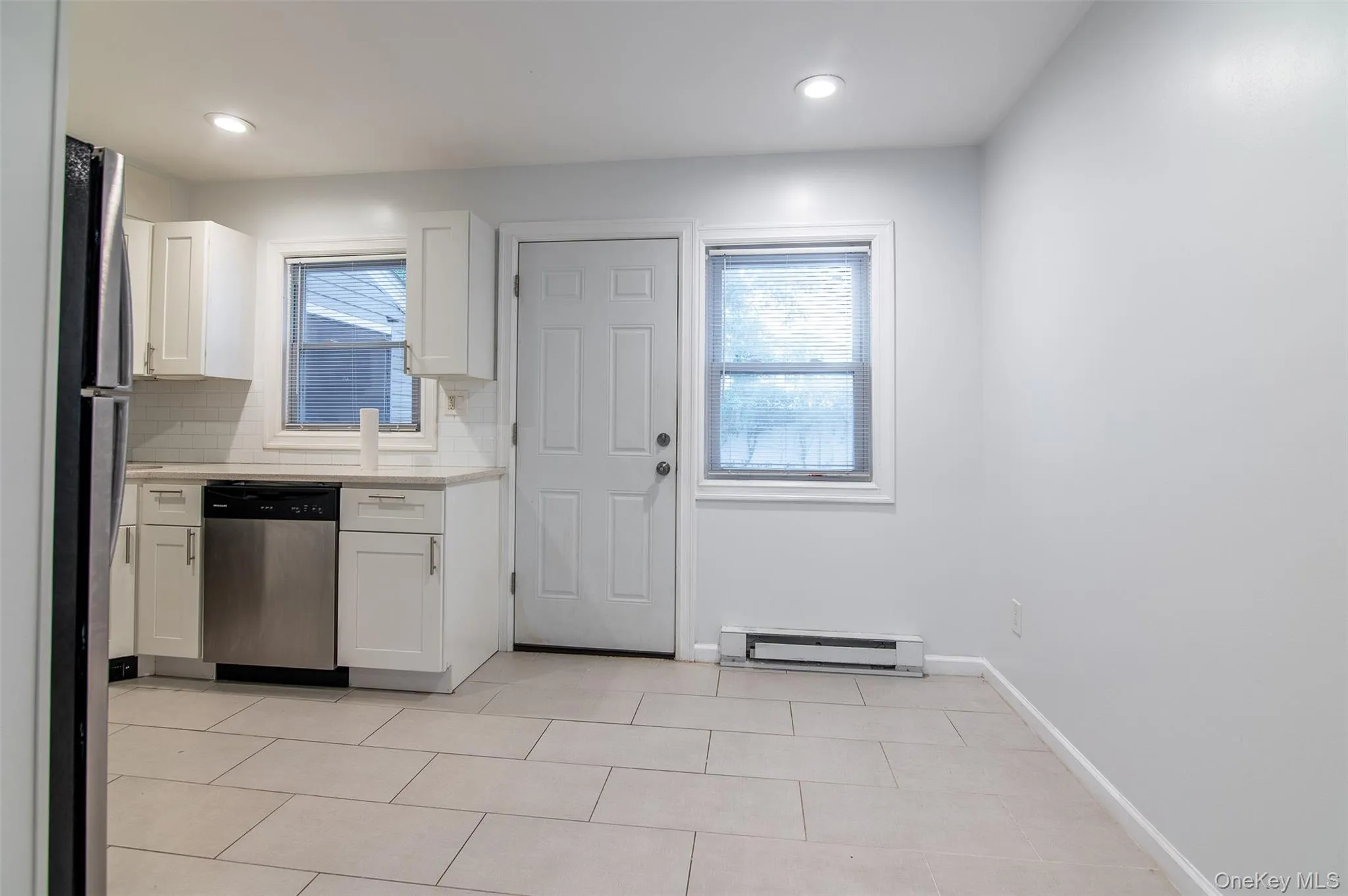 Kitchen with white cabinets, stainless steel appliances, a baseboard heating unit, backsplash, and recessed lighting Kitchen with white cabinets, stainless steel appliances, a baseboard heating unit, backsplash, and recessed lighting