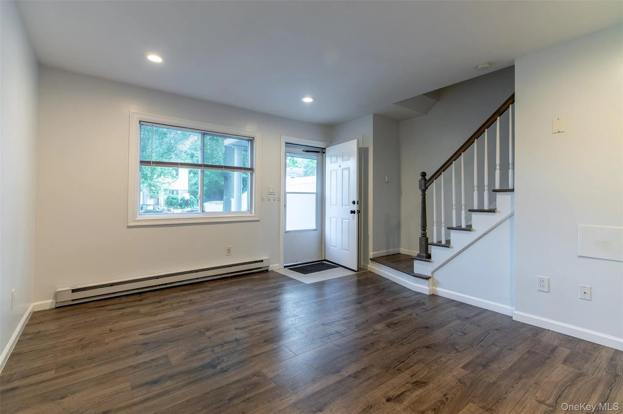 Foyer featuring baseboard heating, dark wood-type flooring, stairs, and recessed lighting Foyer featuring baseboard heating, dark wood-type flooring, stairs, and recessed lighting