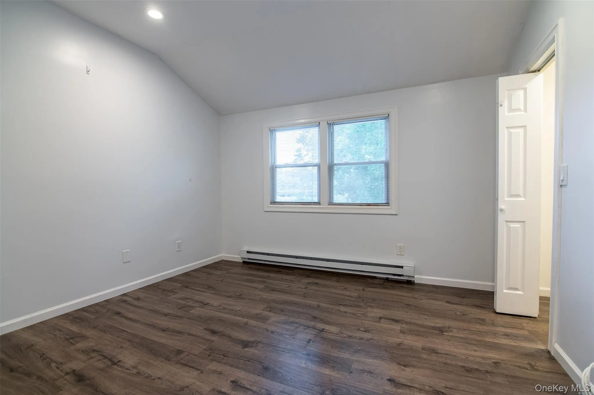 Spare room with a baseboard radiator, lofted ceiling, dark wood finished floors, and recessed lighting Spare room with a baseboard radiator, lofted ceiling, dark wood finished floors, and recessed lighting