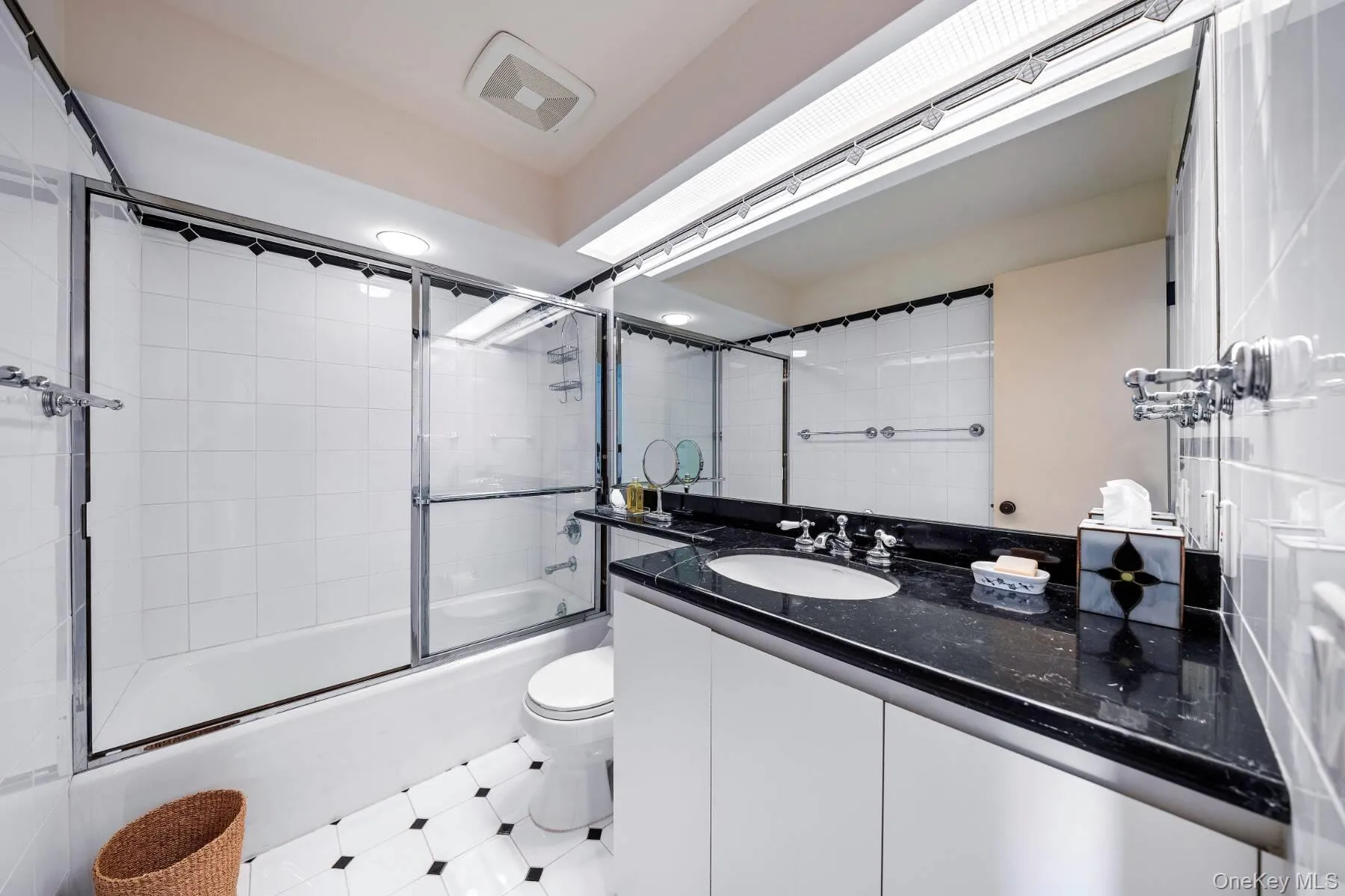 Full bathroom with combined bath / shower with glass door, vanity, and light tile patterned floors Full bathroom with combined bath / shower with glass door, vanity, and light tile patterned floors