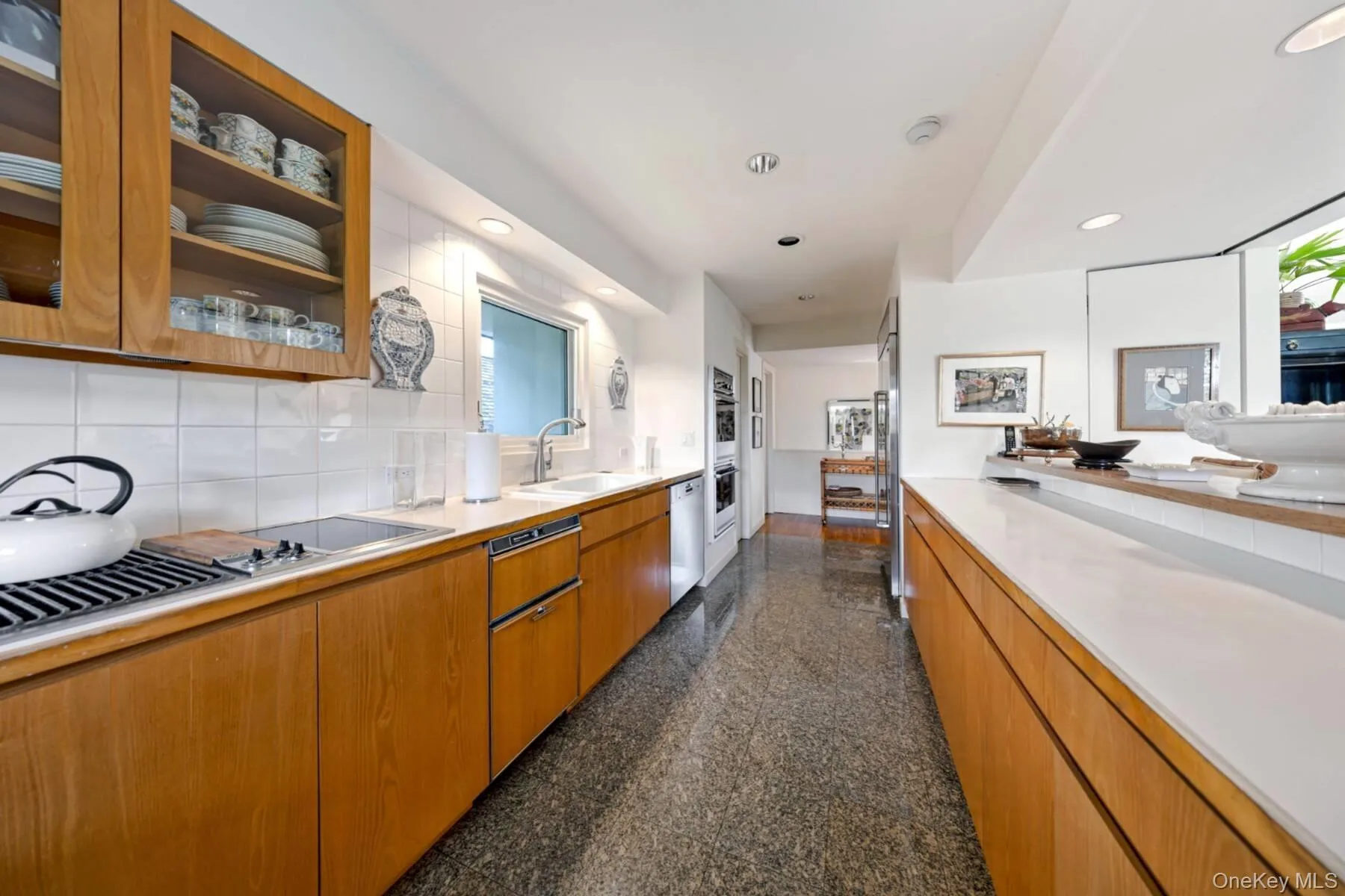 Kitchen with glass insert cabinets, brown cabinetry, granite tiled floors, tasteful backsplash, and recessed lighting Kitchen with glass insert cabinets, brown cabinetry, granite tiled floors, tasteful backsplash, and recessed lighting