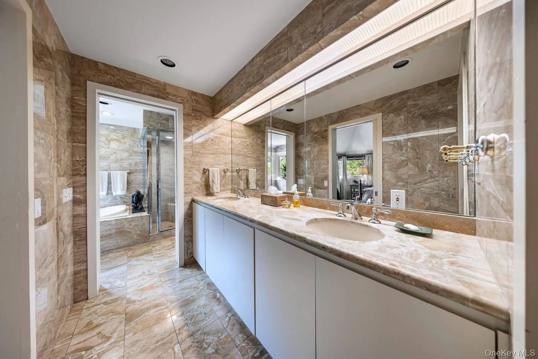 Bathroom with tile walls, a bath, double vanity, and light marble finish floors Bathroom with tile walls, a bath, double vanity, and light marble finish floors