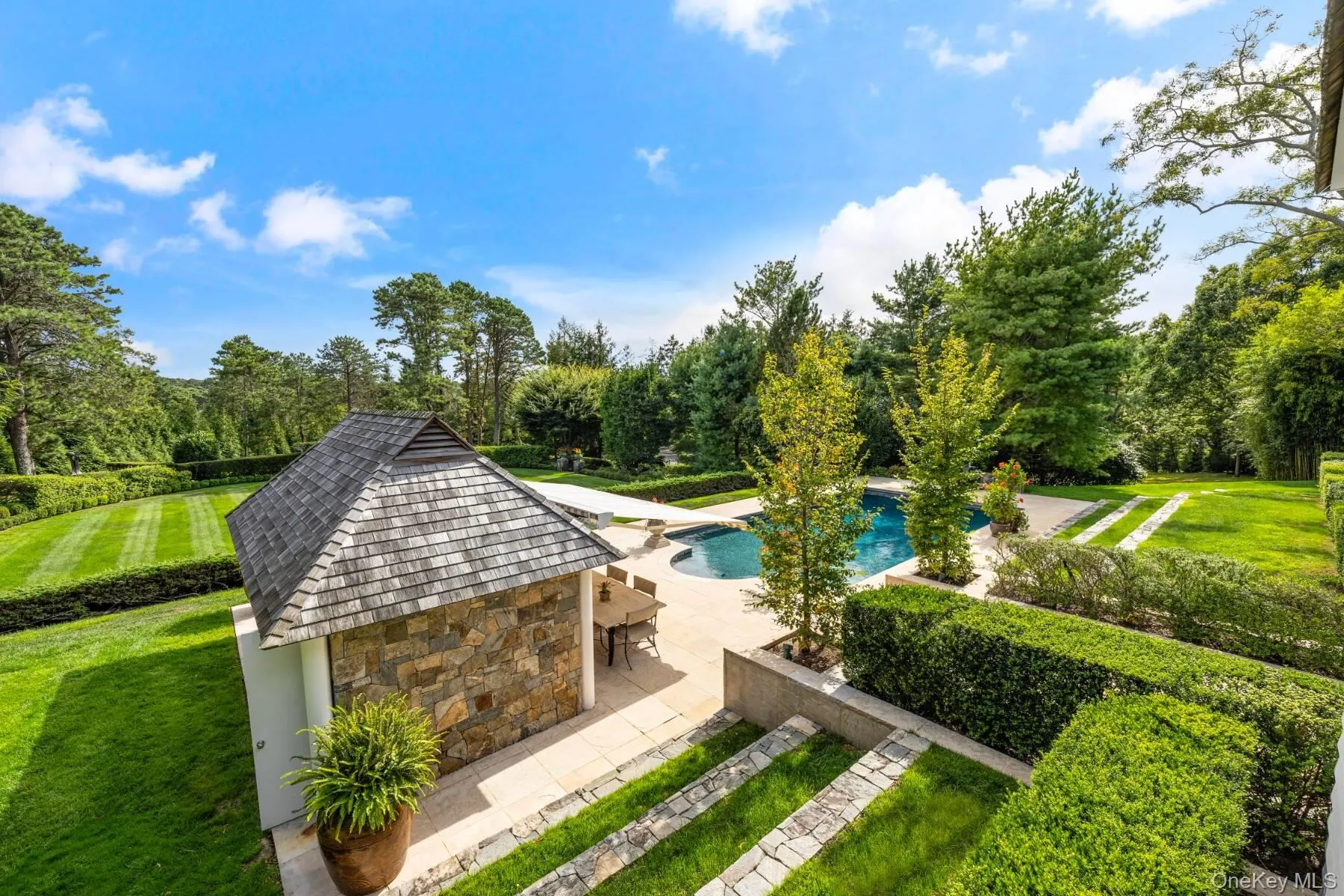 Swimming pool with a lawn, a patio, and view of scattered trees Swimming pool with a lawn, a patio, and view of scattered trees