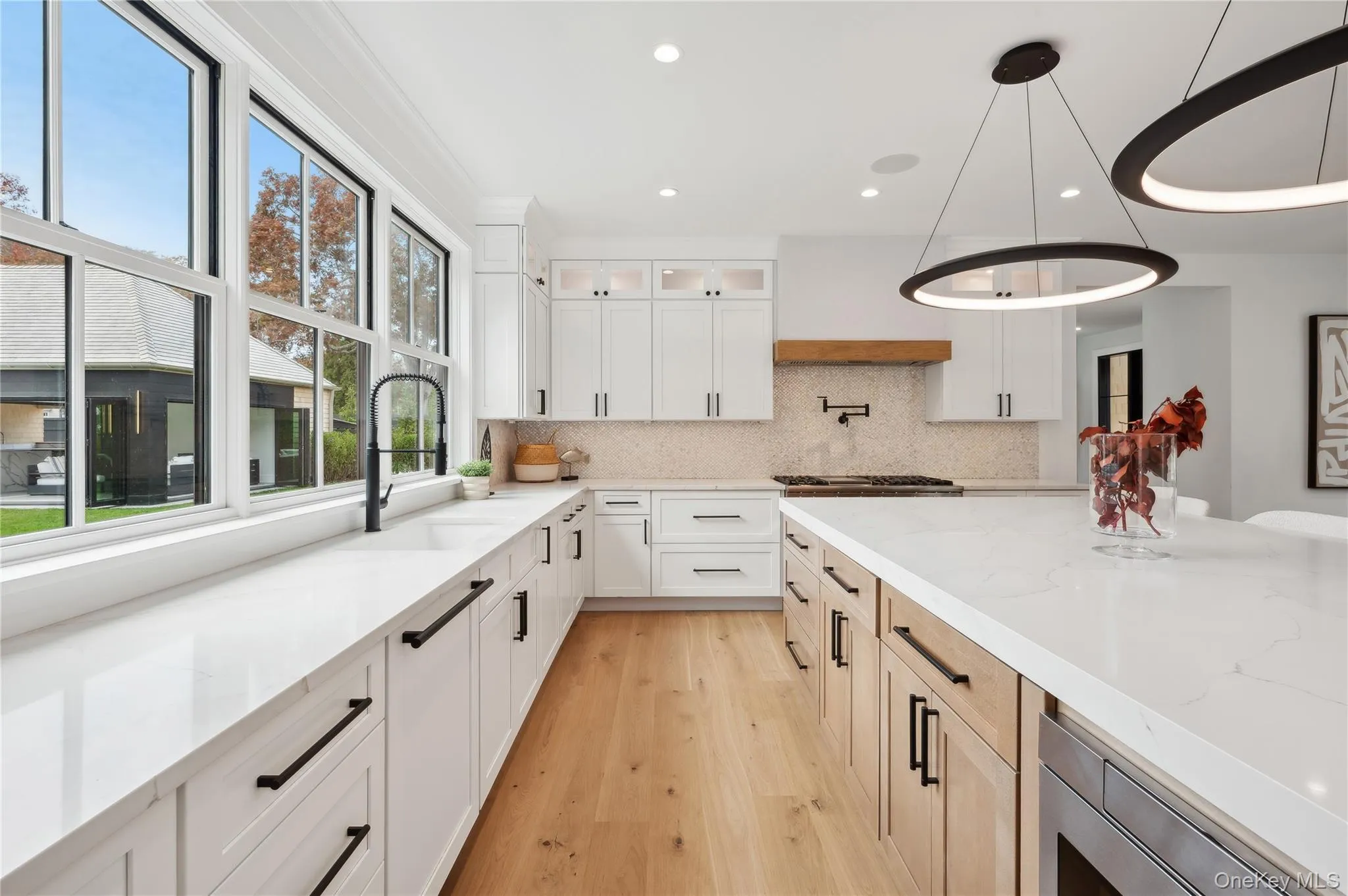 Kitchen with glass insert cabinets, white cabinetry, light stone counters, decorative backsplash, and recessed lighting Kitchen with glass insert cabinets, white cabinetry, light stone counters, decorative backsplash, and recessed lighting