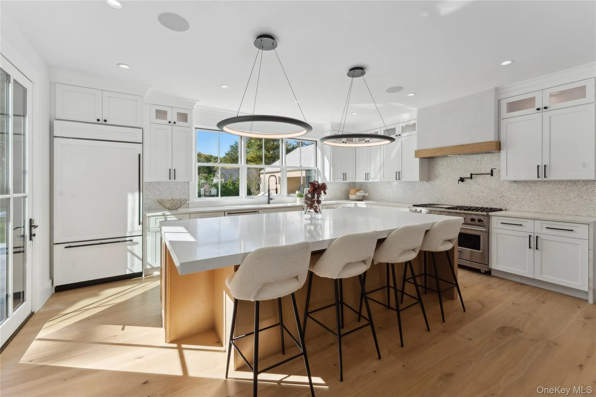Kitchen featuring glass insert cabinets, a kitchen island, light wood finished floors, a kitchen bar, and recessed lighting Kitchen featuring glass insert cabinets, a kitchen island, light wood finished floors, a kitchen bar, and recessed lighting