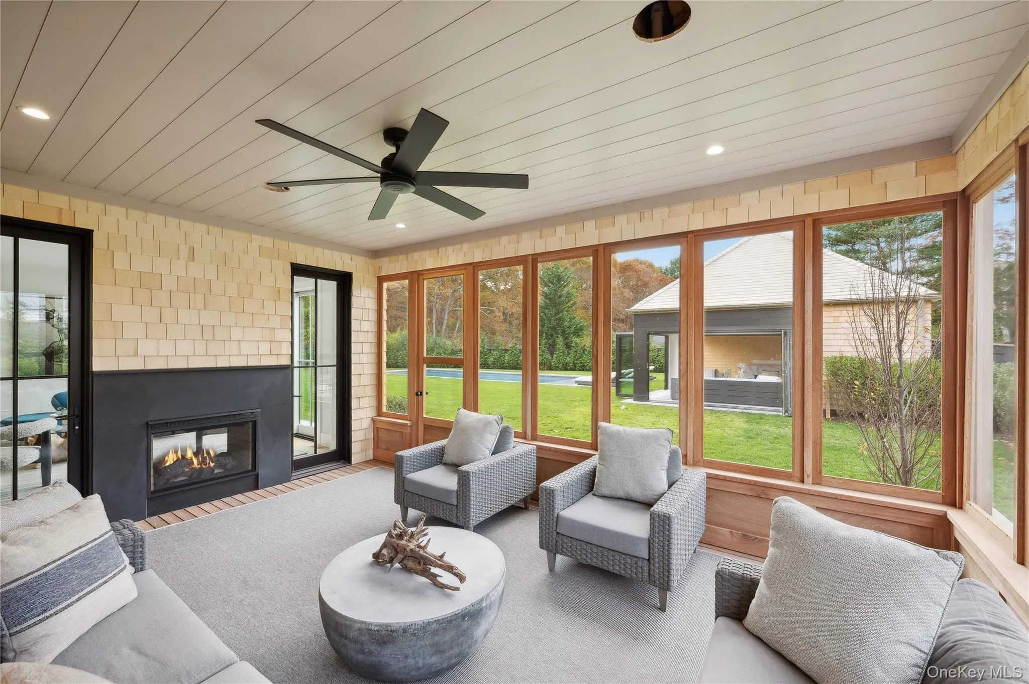Sunroom / solarium with an outdoor living space with a fireplace and ceiling fan Sunroom / solarium with an outdoor living space with a fireplace and ceiling fan