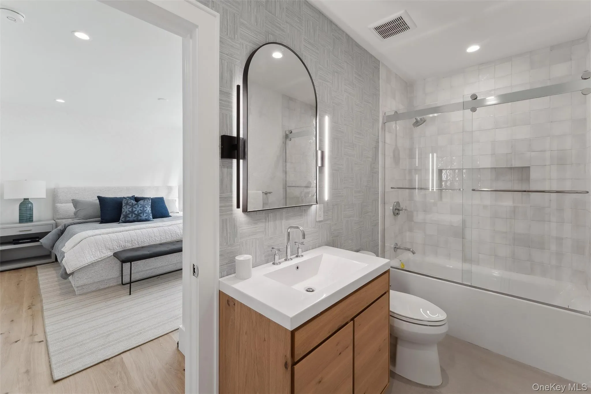 Bathroom with shower / bath combination with glass door, vanity, connected bathroom, recessed lighting, and tile walls Bathroom with shower / bath combination with glass door, vanity, connected bathroom, recessed lighting, and tile walls