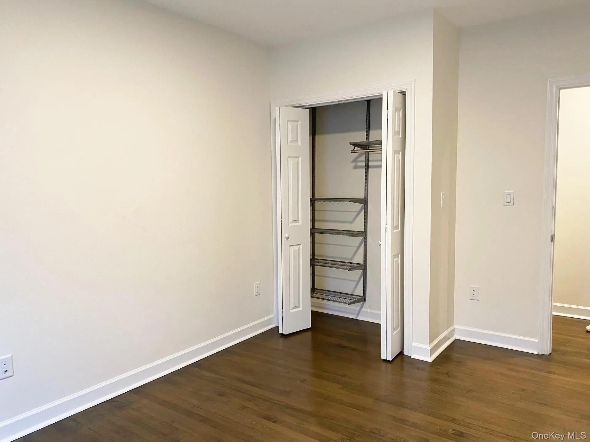 Unfurnished bedroom with dark wood-style floors and a closet Unfurnished bedroom with dark wood-style floors and a closet