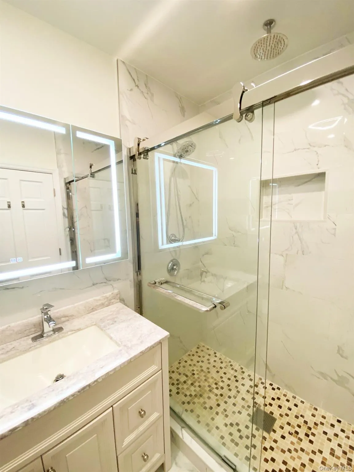 Full bathroom with a marble finish shower and vanity Full bathroom with a marble finish shower and vanity
