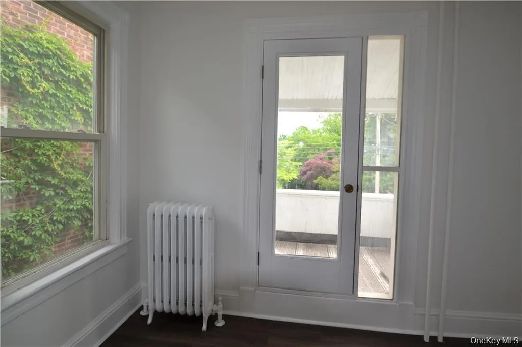 Doorway to outside with radiator heating unit and wood finished floors Doorway to outside with radiator heating unit and wood finished floors